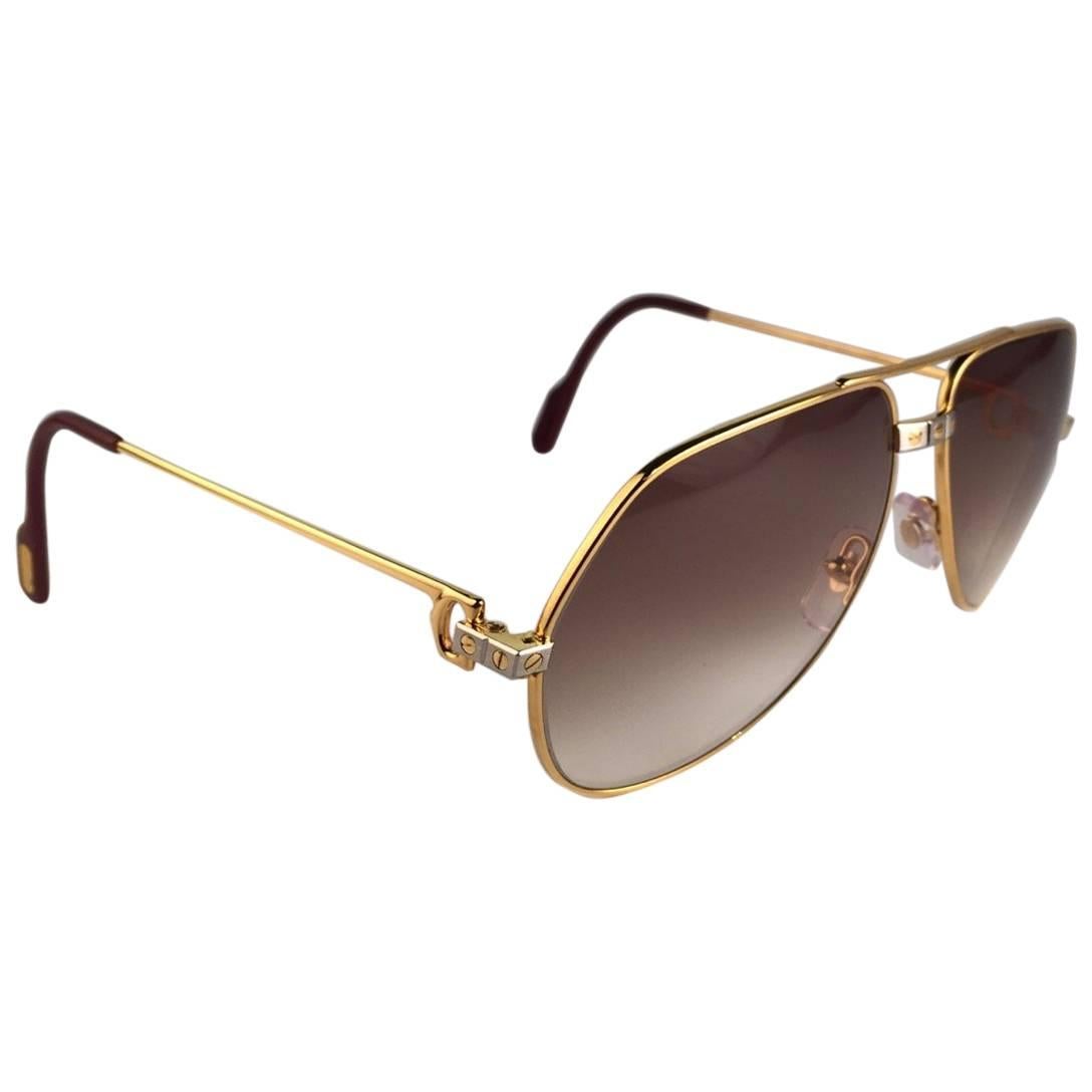 Cartier Aviator Santos Sunglasses with Brown Gradient (uv protection) Lenses.  

Frame is with the famous screws on the front and sides in yellow and white gold. All hallmarks. Red enamel with Cartier gold signs on the ear paddles.  Both arms sport