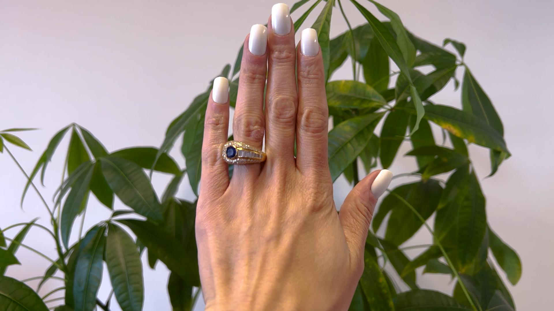 Un Anillo Cartier Vintage de Zafiro y Diamante de Oro Amarillo de 18k. Con un zafiro redondo de talla mixta con un peso aproximado de 1.10 quilates. Acentuado por nueve diamantes talla baguette y 113 diamantes talla brillante redondos con un peso