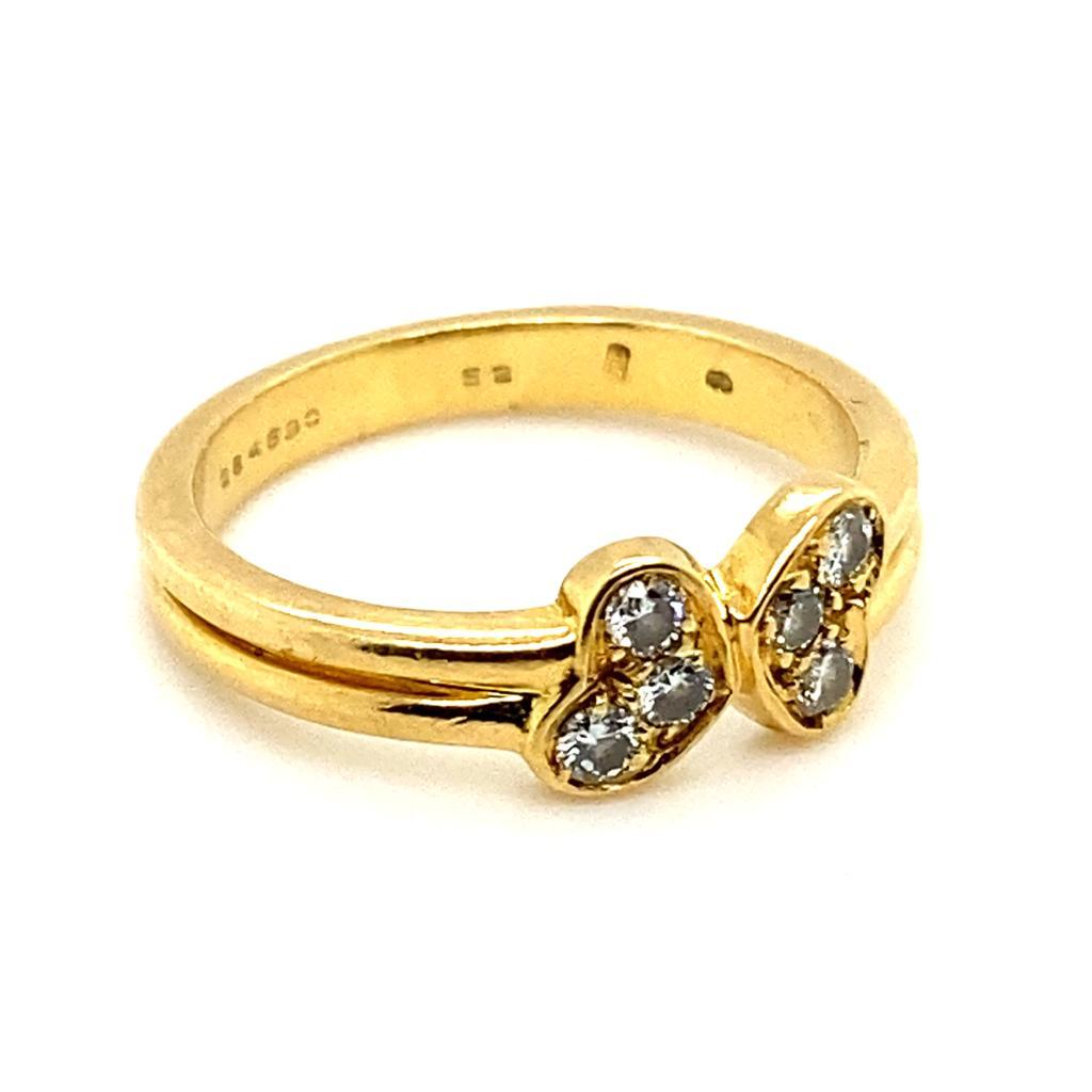 A vintage Cartier six stone diamond love heart ring in 18 karat yellow gold.

The ring is designed as a pair of love hearts; each of which has been grain set with a trio of round brilliant cut diamonds leading onto a plain polished split 18 karat