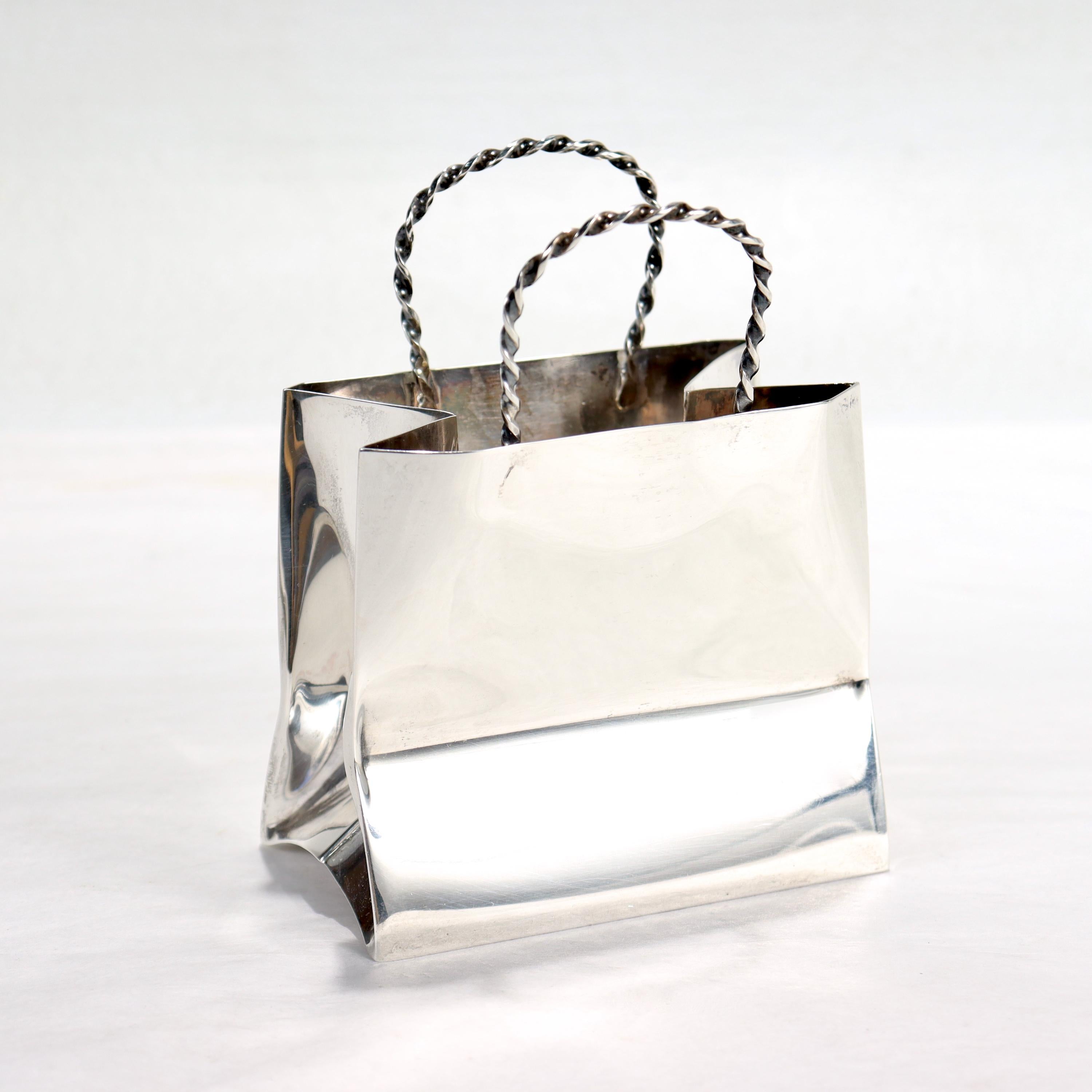 A fine vintage miniature shopping or gift bag.

By Cartier.

In sterling silver.

With slightly crumpled sides and braided handles

Perfect for the bar as a cocktail pick holder or on the vanity!

Date:
Mid to Late 20th Century

Overall