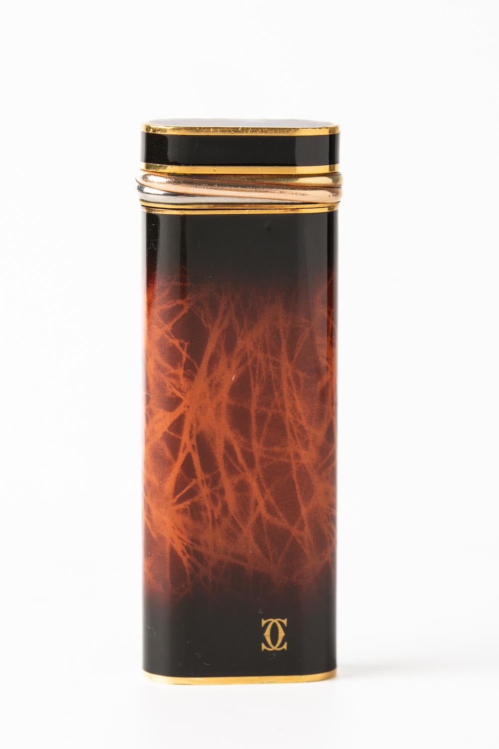 Very rare and luxurious classic Cartier “Trinity” lighter with a light brown flame design and three ring band at the top.  Inscribed with 'Cartier Paris' along the bottom edge with a serial number: 90279X. The lighter 

The lighter is in working
