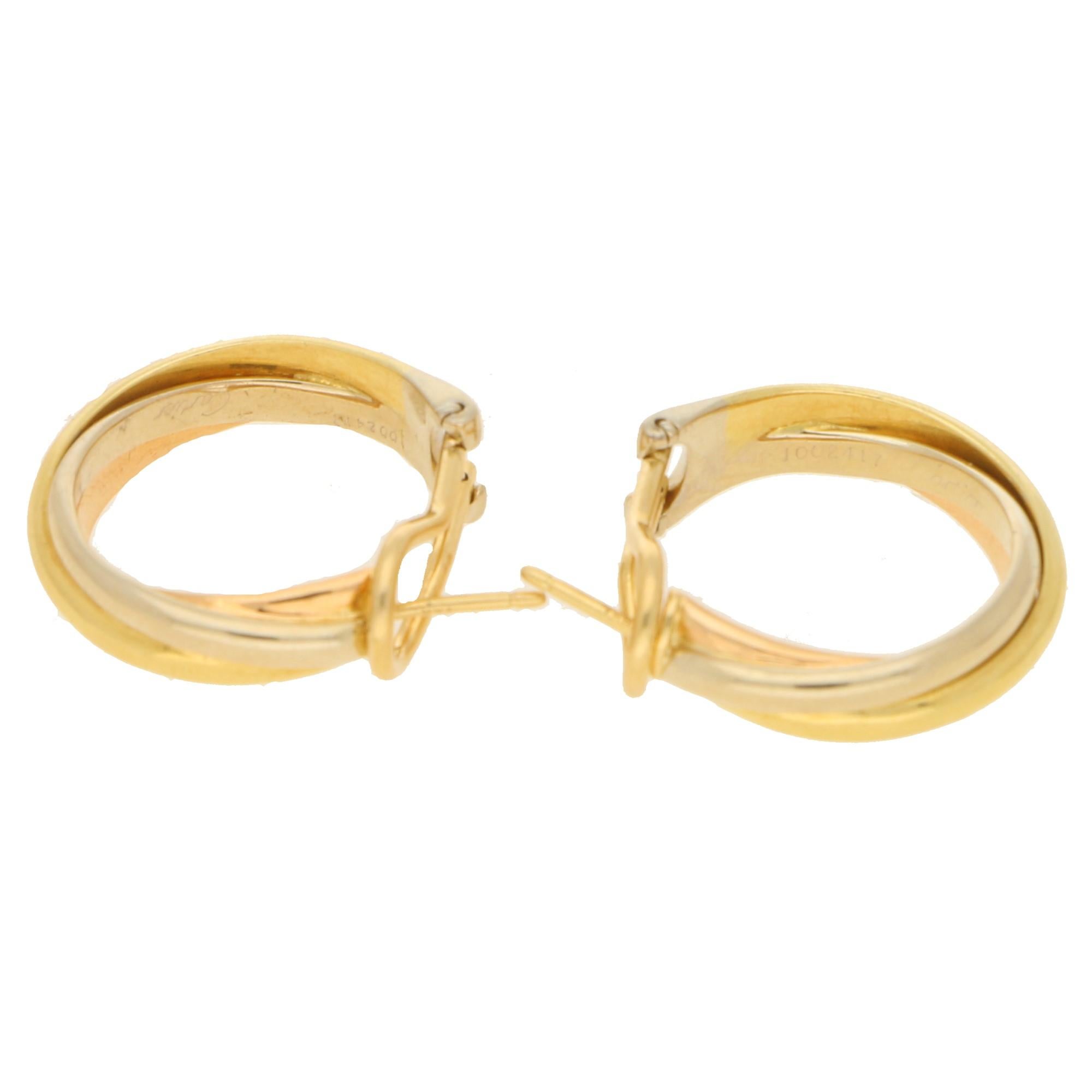 A pair of classic Vintage Cartier Trinity Hoop earrings with en-twinned bands of 2.5mm yellow, rose and white gold which are secured with a looped hinged backing with post, and signed inside both sides 750 Cartier.
Measuring approximately 23mm in