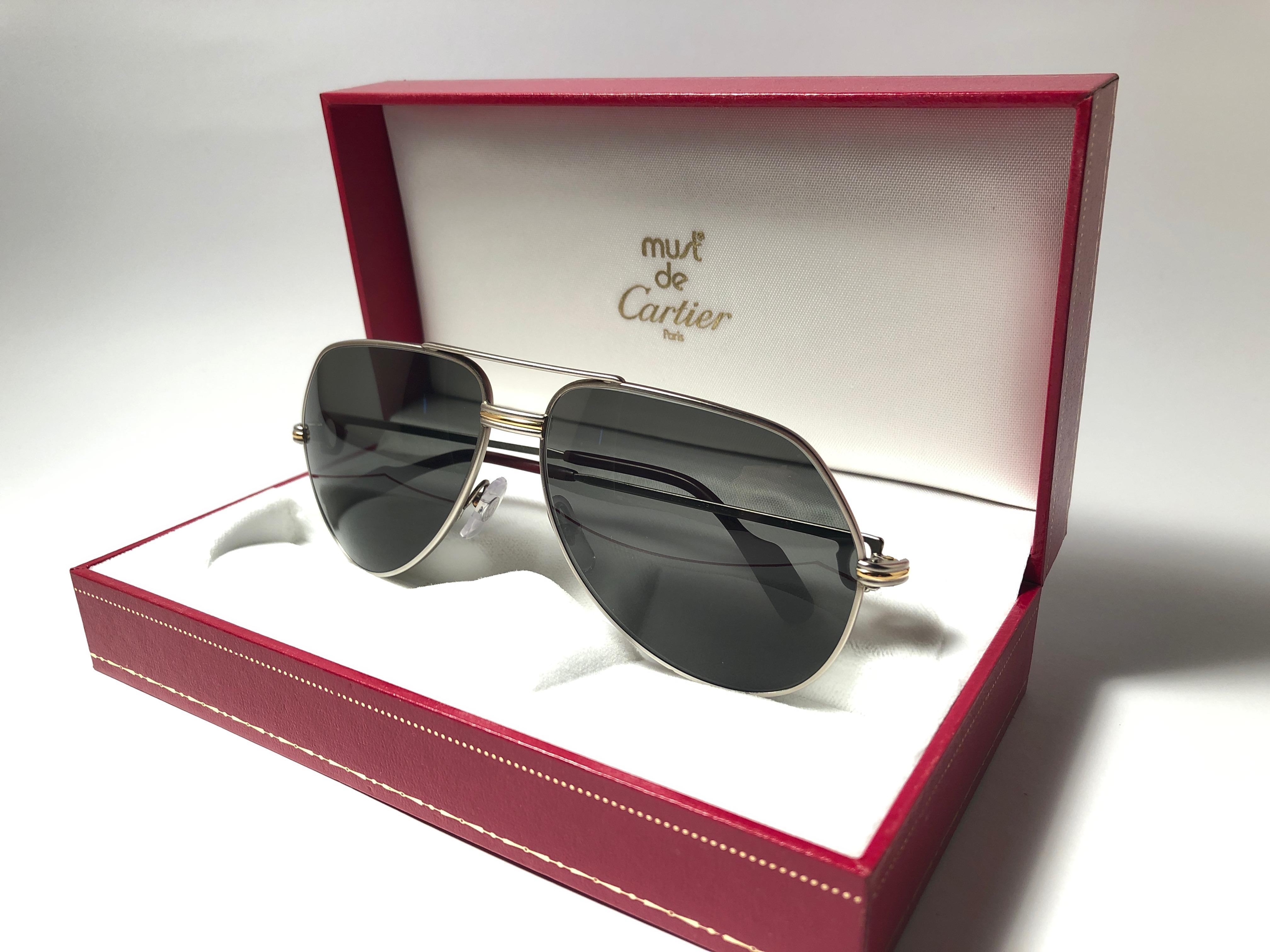 Vintage Cartier Aviator Vendome 59MM titanium sunglasses with grey (uv protection) Lenses.  Frame is with the famous Vendome stripes on the front and sides in yellow and white gold. 
All hallmarks. 
Red enamel with Cartier gold signs on the ear