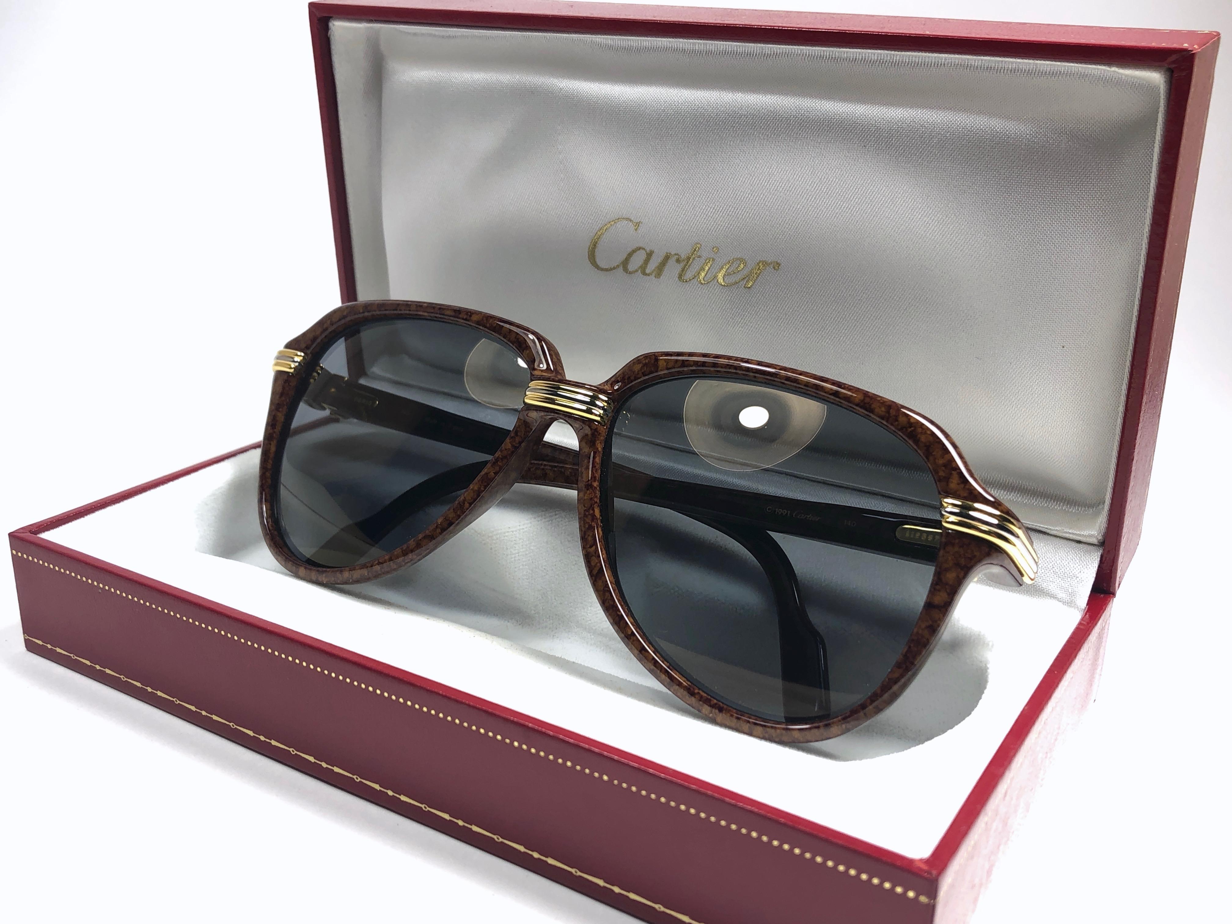 Sammlerstück. Einzigartige und originelle Cartier Aviator Vitesse Sonnenbrille, die Brown Jaspe Edition mit Akzenten aus Gelb- und Weißgold. Original Cartier graue Gläser.
Der Rahmen ist an den Seiten in Gold. Alle Markenzeichen. Cartier-Goldzeichen