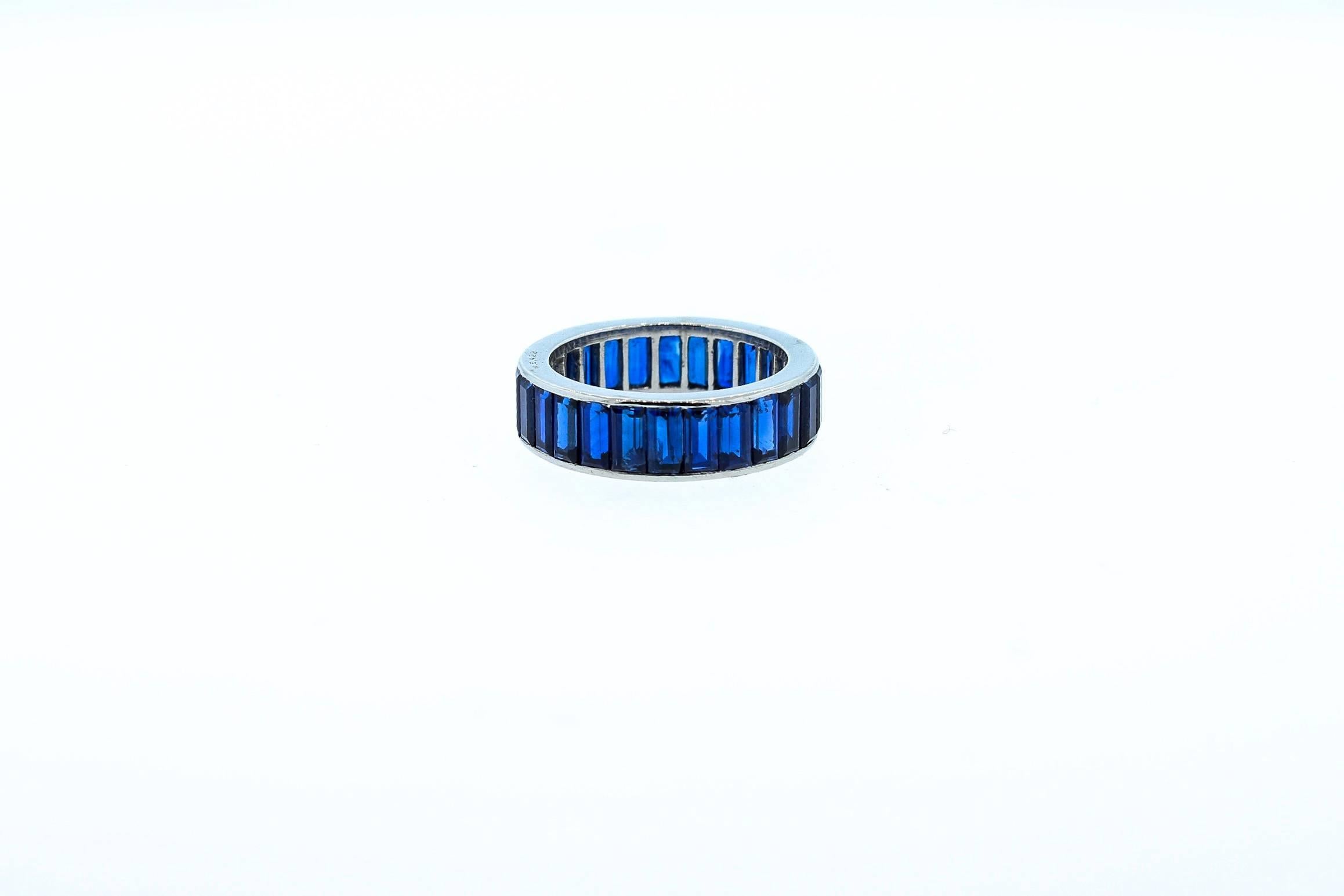 A rare baguette cut blue sapphire wedding band by Cartier London circa 1960.  This wide band is a collection of beautiful blue sapphires, 27 baguettes weighing a total of approximately 8 carats.  The band is made in platinum.  It is signed Cartier