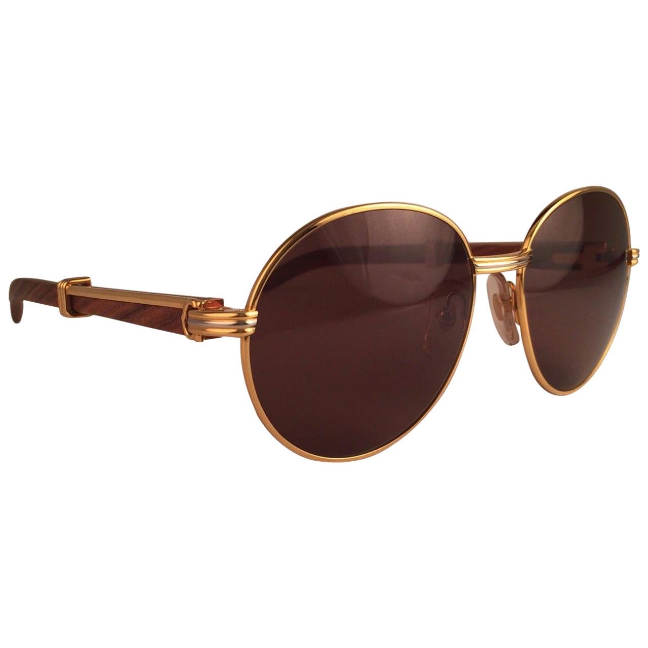 Original 1990 Cartier Bagatelle Wood Sunglasses from the coveted Precious Wood series with wood temples and honey brown (uv protection) lenses. 
The frame has the front and sides in yellow and white gold. All hallmarks. gold Cartier signs on the ear