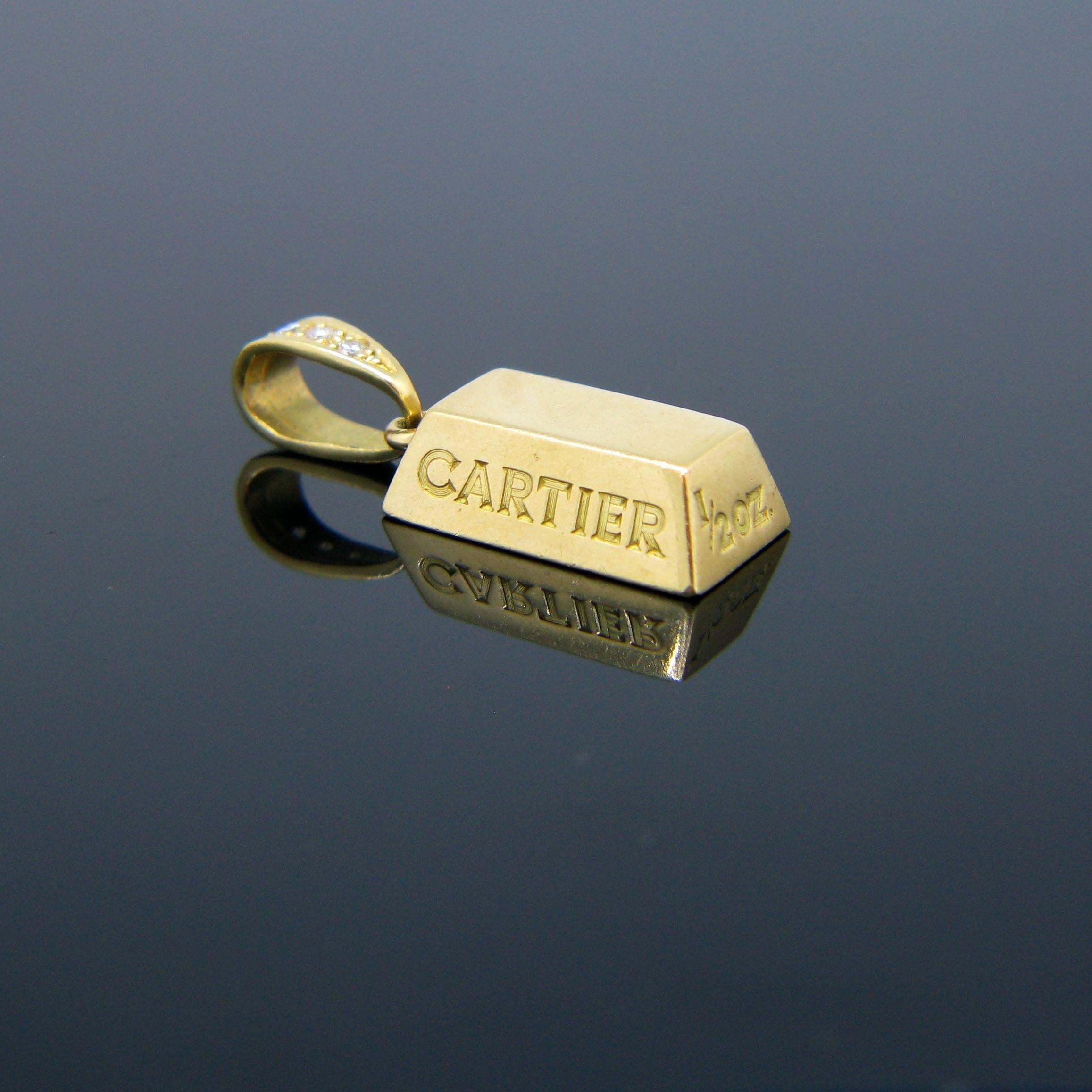 This pendant signed Cartier is a half-ounce gold bar or ingot. It is fully made in 18kt yellow gold. The bale is set with three round cut diamonds. It is signed and numbered Cartier 140592 at the back. It is also engraved with Cartier on one of the