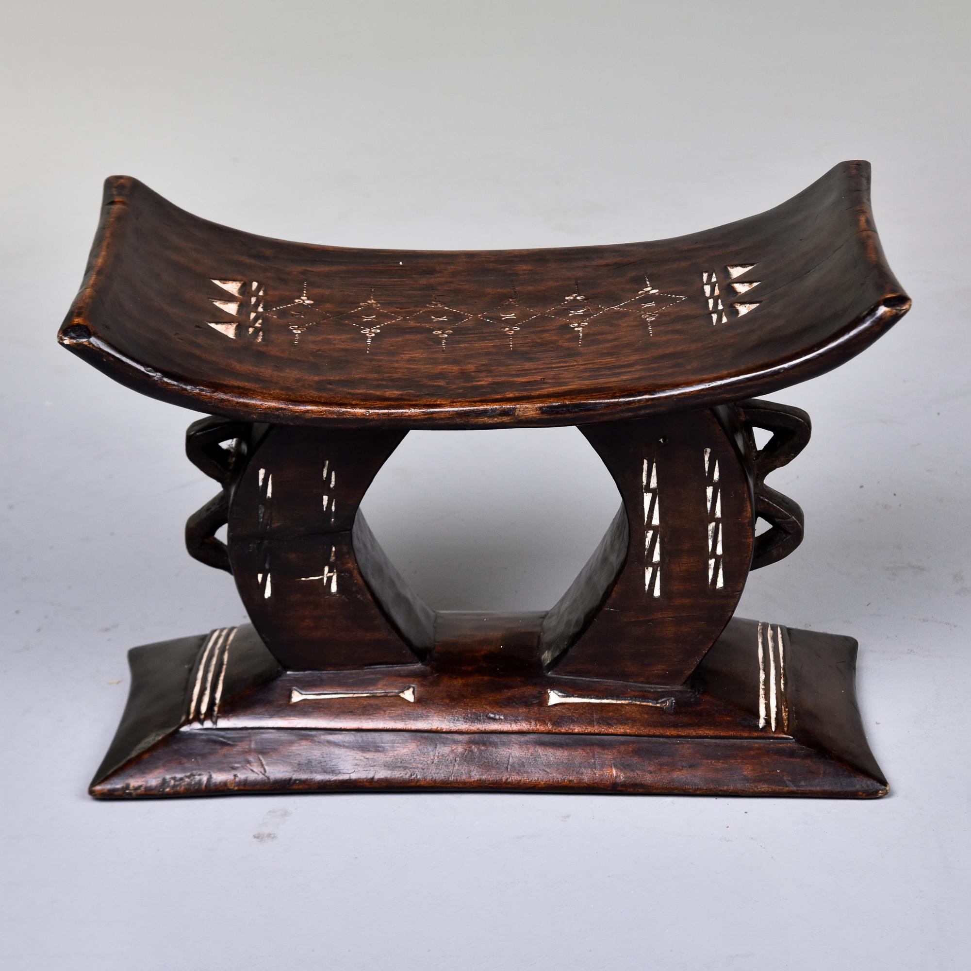 This Ashanti carved stool dates from the 1980s and was found in Ghana. Hand carved and crafted from a single piece of wood, this stool has white painted and etched detailed design on the seat and base. Unknown wood type is dense and sturdy with a