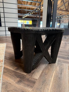 Taburete vintage de madera negra africana tallada con diseño en forma de «X»