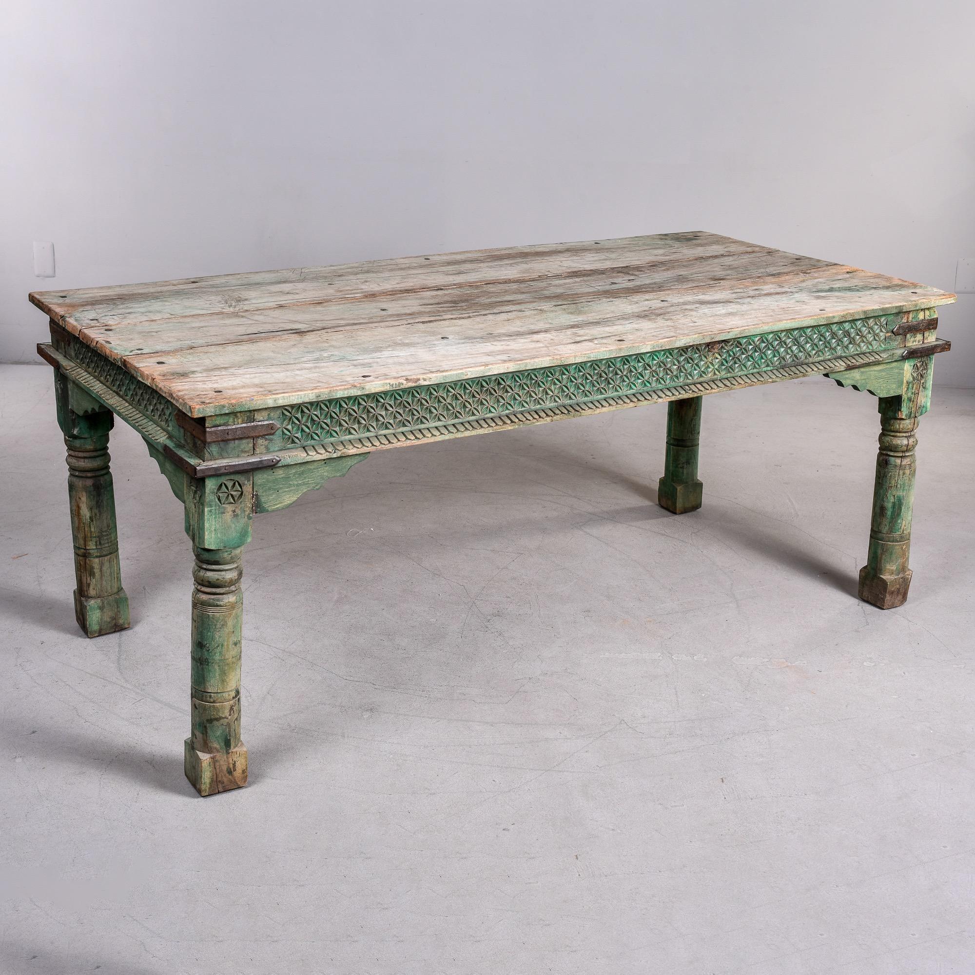 Found in the United States, this early 20th century painted and carved dining table appears to be of Indian origin dating from the 1930s or so. Farm style rustic table has original faded and worn green paint, substantial turned legs with block feet