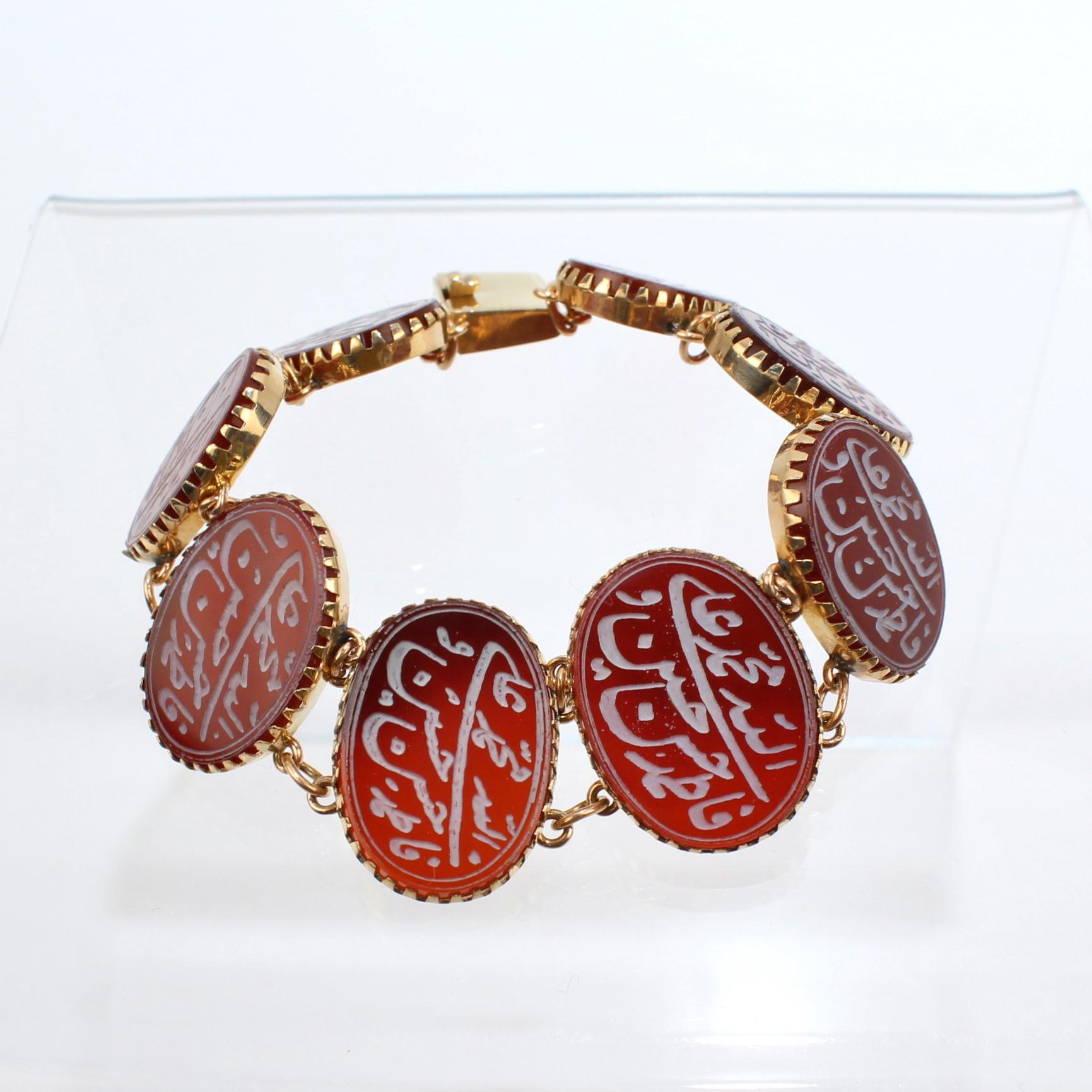 A very fine carved Carnelian amulet bracelet.

With oval carnelian amulets that are bezel set in 14k gold.  

Each flat carnelian cabochon is carved with Arabic inscriptions the holy names in Islam of Allah, Mohammed, Ali, Fatima, Hassan,