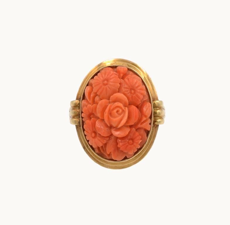 A vintage 14 karat yellow gold ring from circa 1920. This pretty ring features coral in a beautiful carved floral pattern. 
Currently a US size 8 and easily adjustable.
This ring measures approximately 0.44 inches in depth (measured from when worn