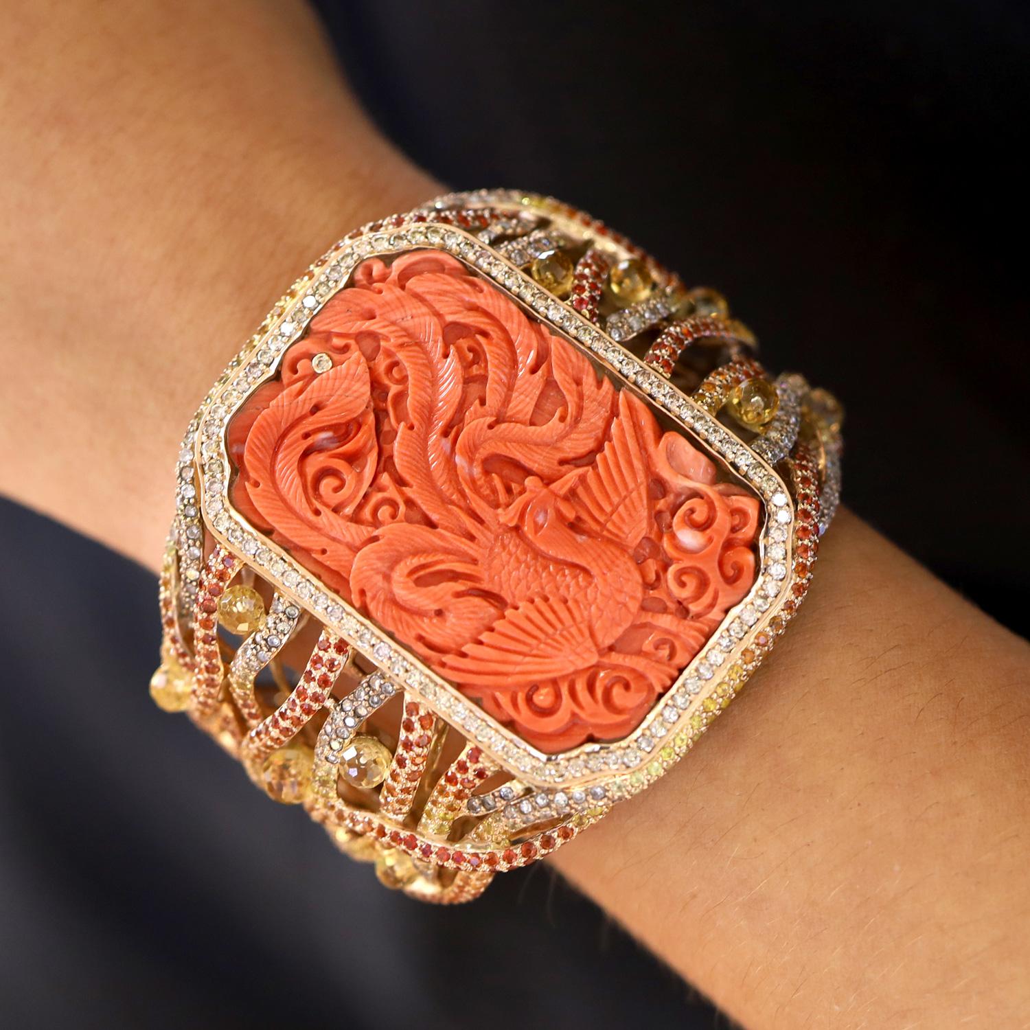 Una espectacular pulsera estilo brazalete vintage de coral, diamantes y zafiros fantasía con una gloriosa procedencia. Centrada por una antigua talla china de un ave fénix rodeada de numerosos diamantes entrelazados con un colorido conjunto de