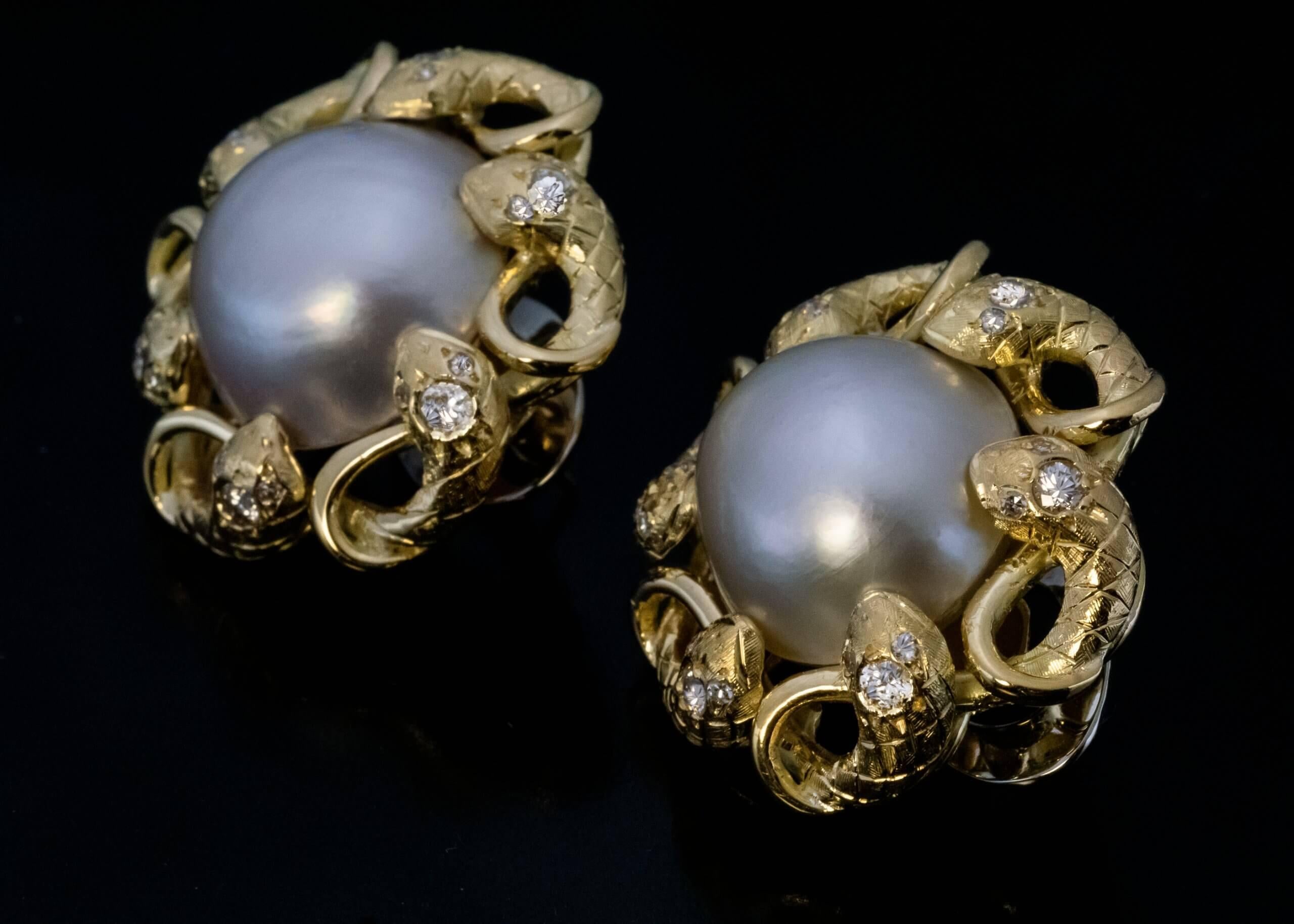 Circa 1960s  These finely crafted 18K yellow and white (omega clips) gold snake motif earrings are centered with two mabe pearls. The pearls are surrounded by hand engraved coiled snakes embellished with diamonds.  Estimated total diamond weight is