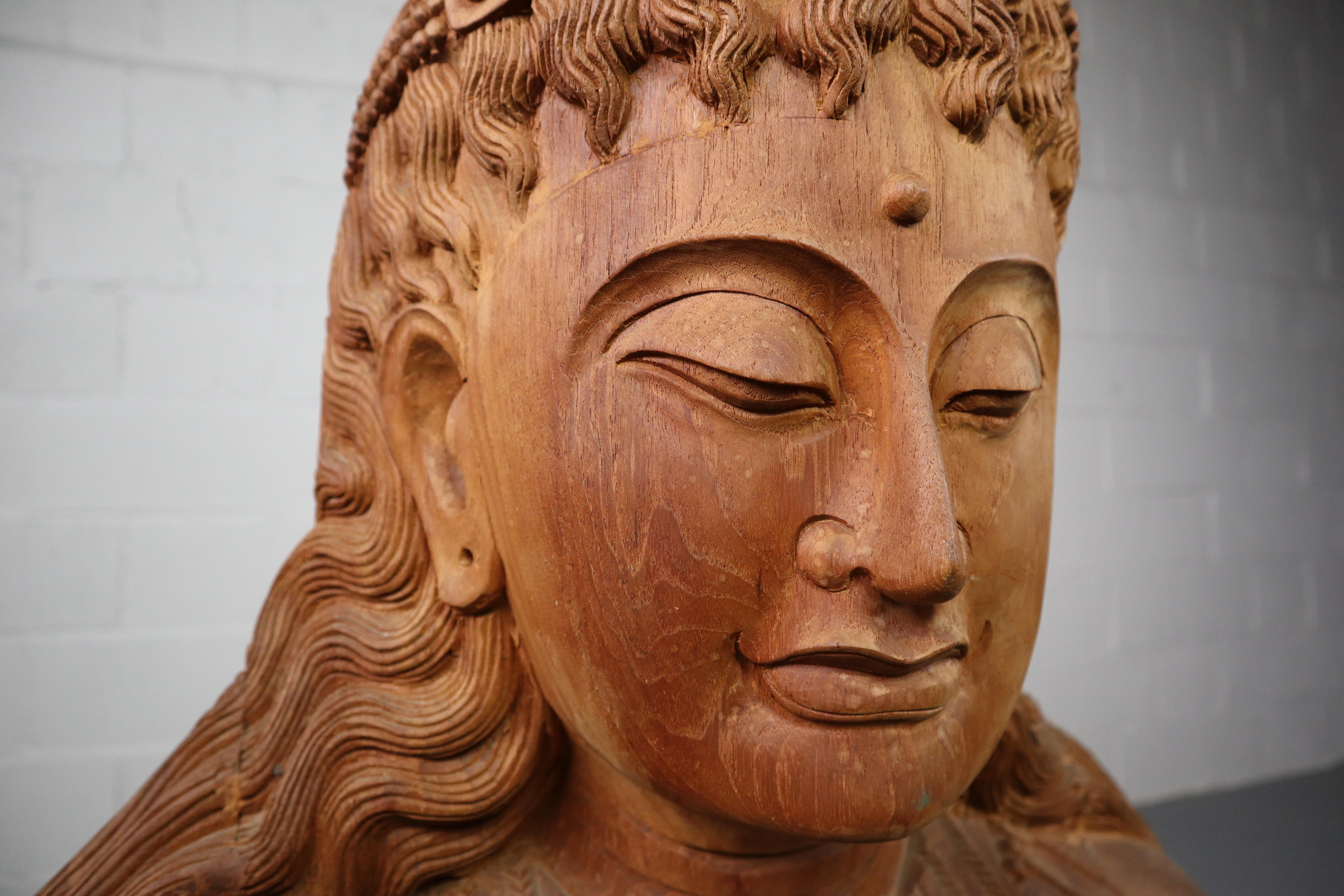 A vintage hardwood carved Buddha bust sculpture decorative object.