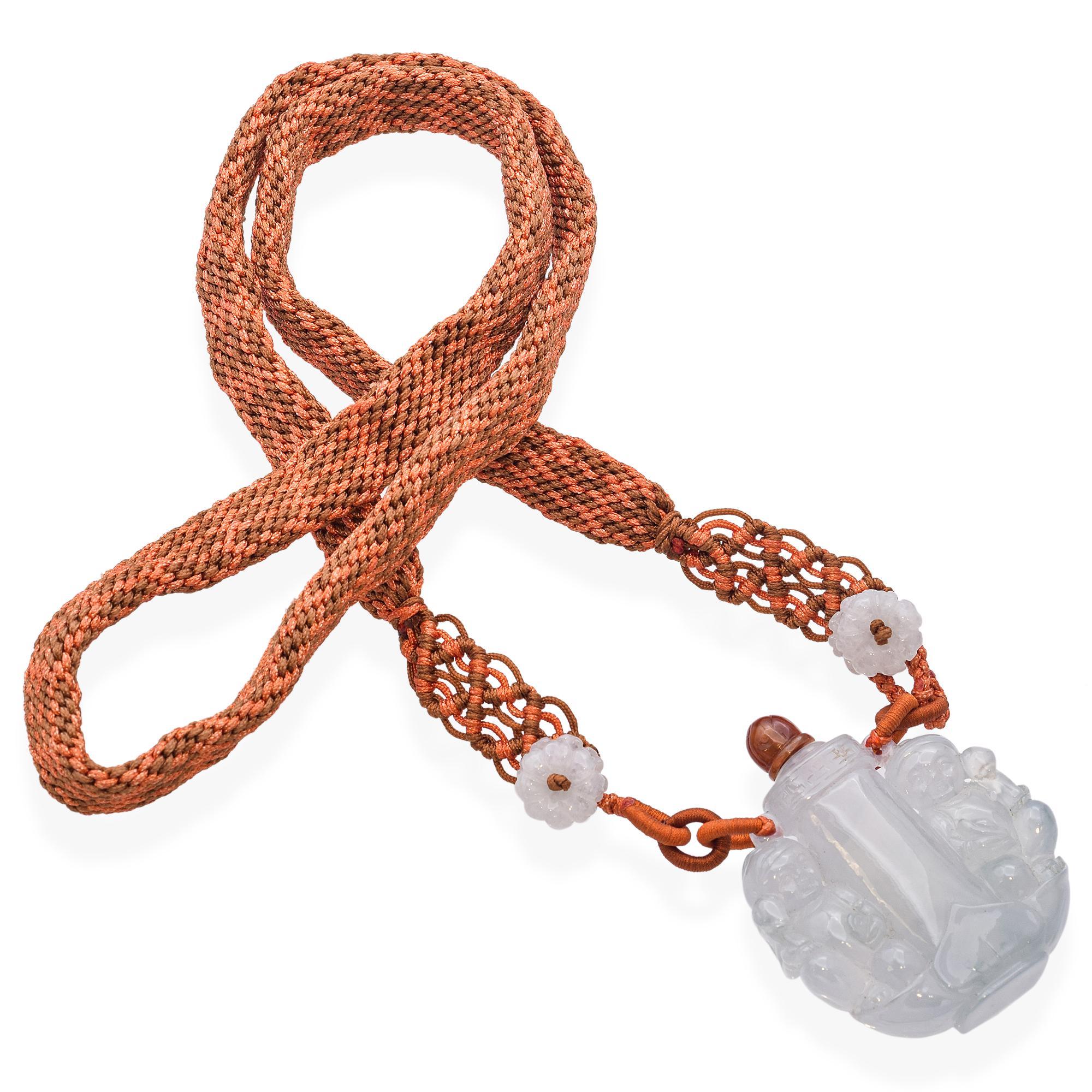 Diese Jade-Halskette mit Schnupftabakfläschchen zeigt eine kunstvoll geschnitzte Szene mit zwei Buddha-Babys - eines hält eine Schlange, das andere ein Tablett -, die eine zentrale, mit Blumenmotiven verzierte Säule umkreisen. Die fein