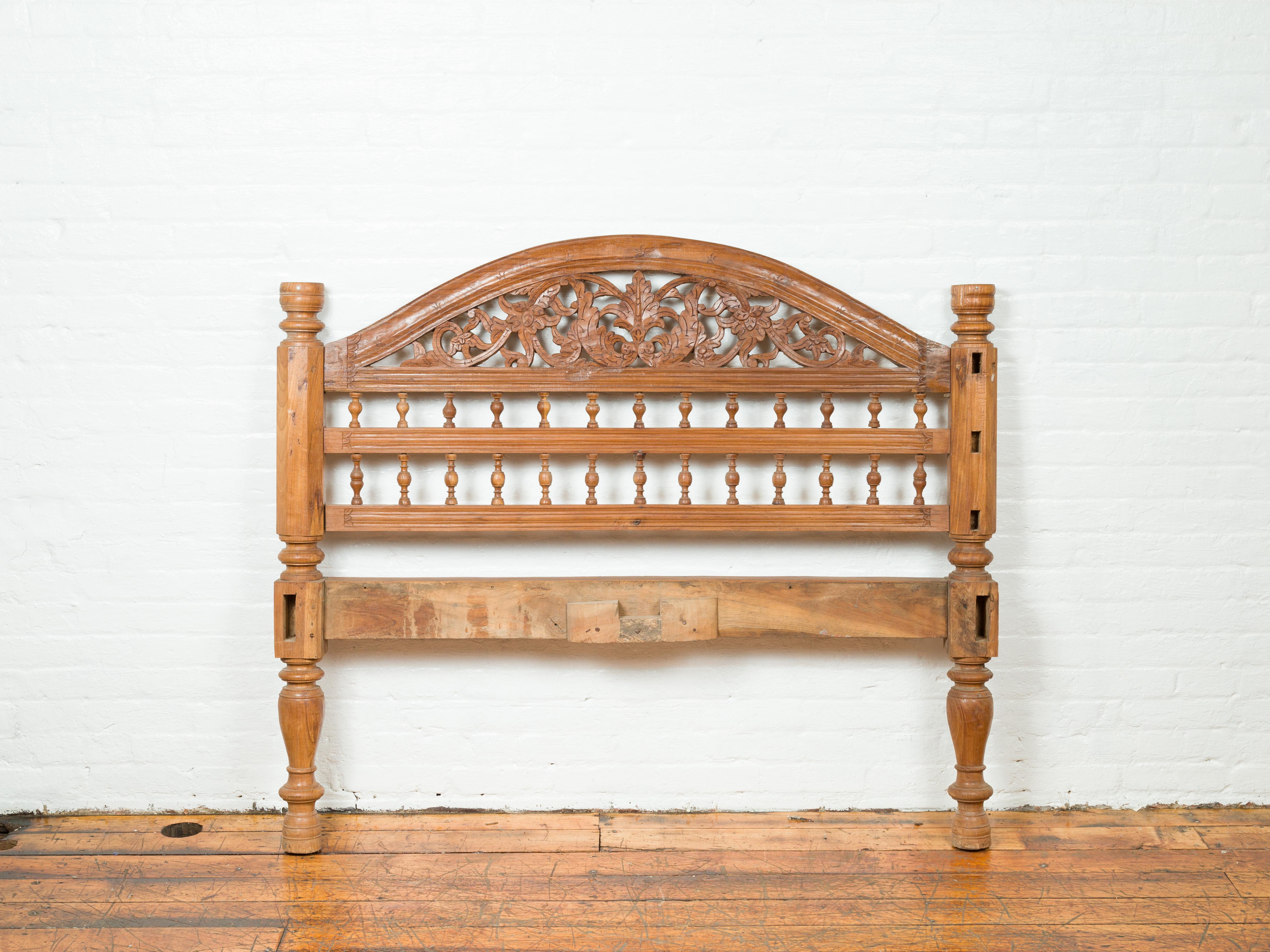 A carved vintage Indonesian headboard from the mid-20th century, with scrolling foliage and petite balusters. Crafted in Indonesia, this carved wooden headboard that could possibly fit a full bed, features a bonnet-shaped upper rail, resting upon