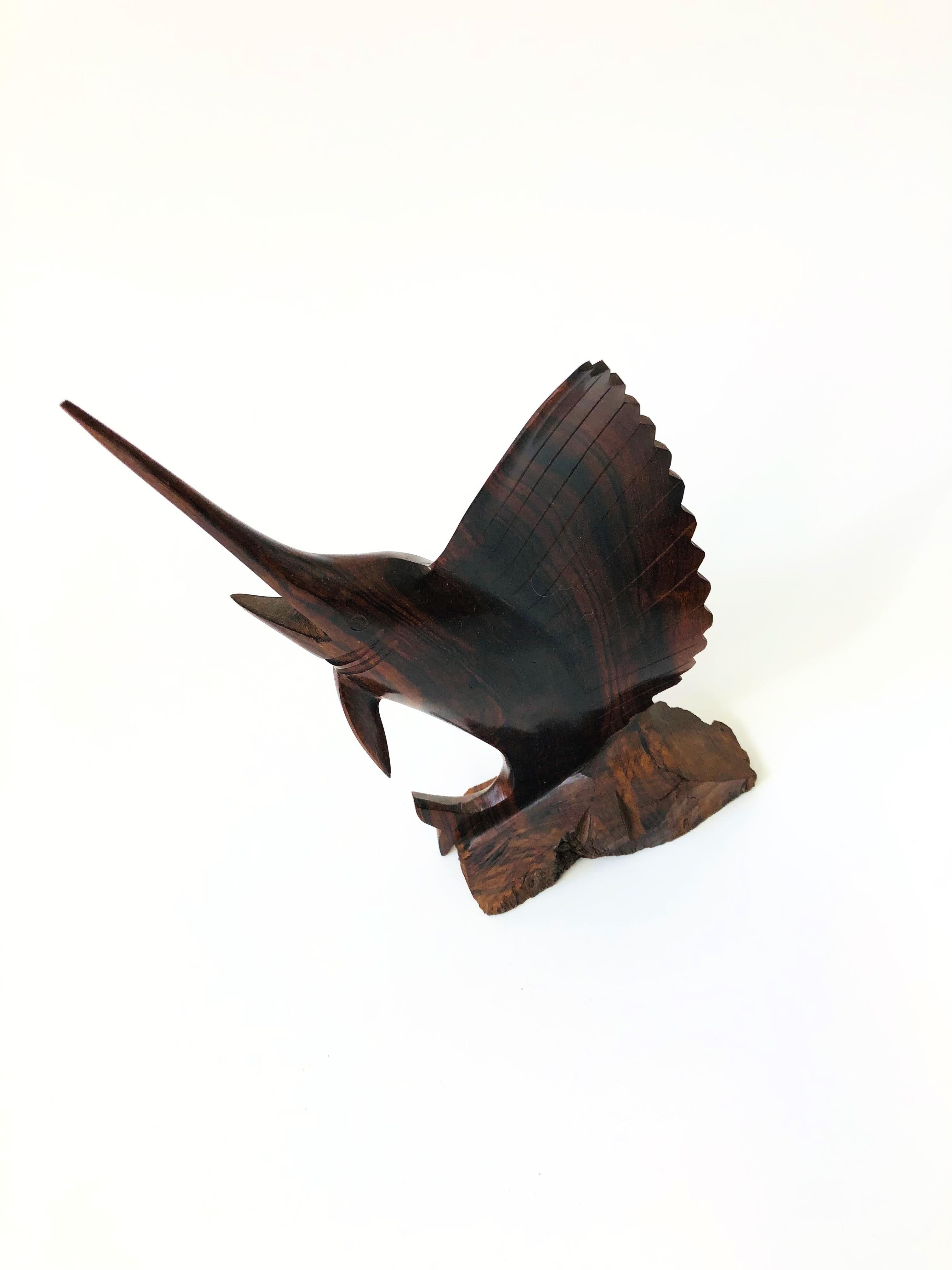 A vintage carved ironwood statue of a marlin. Great detailing to the fish's features with a lovely dark natural grain and smooth finish to the wood that contrasts nicely with a natural wood base.
 