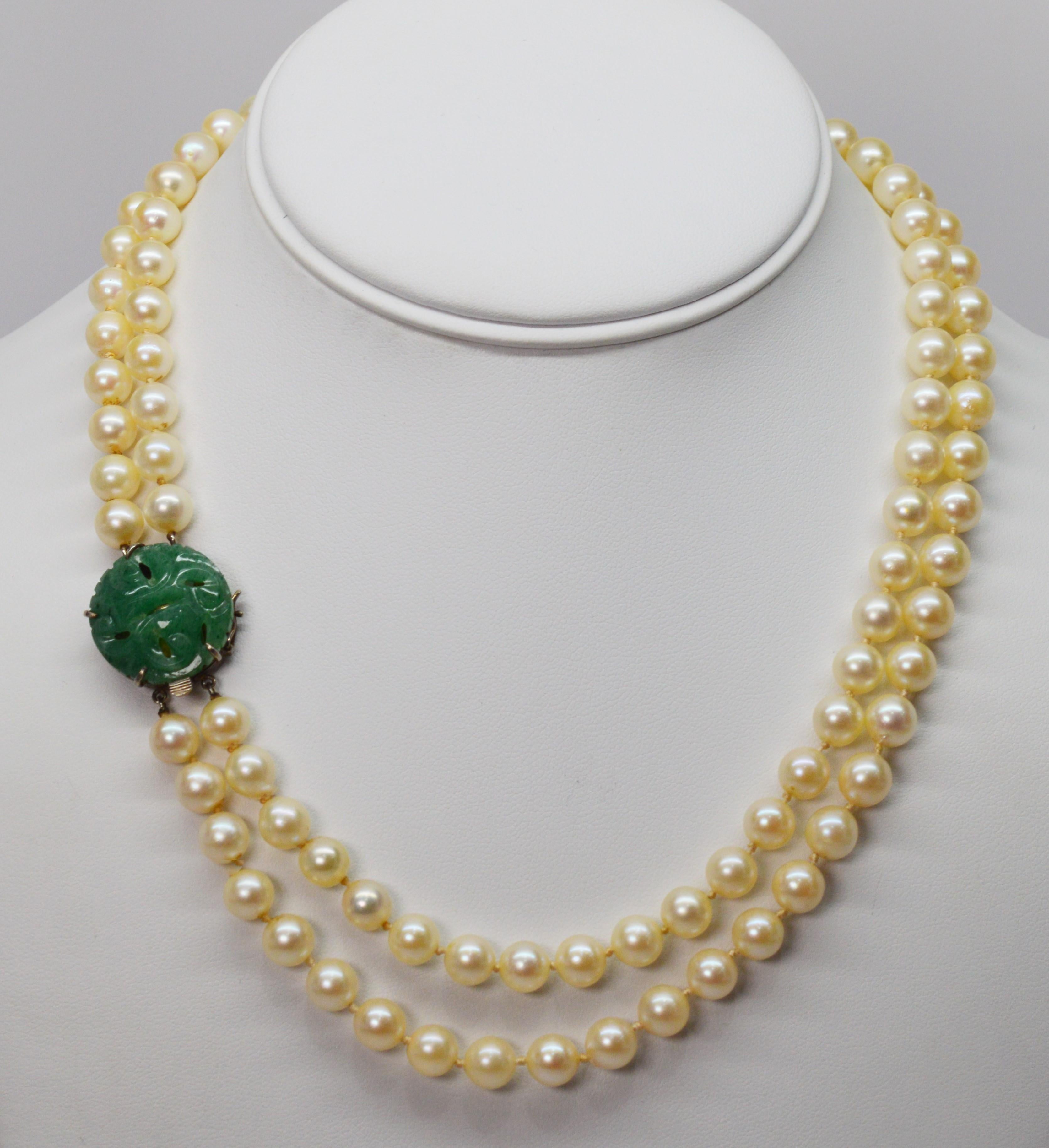 A striking hand carved jade decorative clasp mounted in silver is the focal point of this vintage double strand eighteen inch necklace of fifty 7 mm hand strung pearls. The ornate jade box clasp with safety clip measures approximately 3/4 inch round