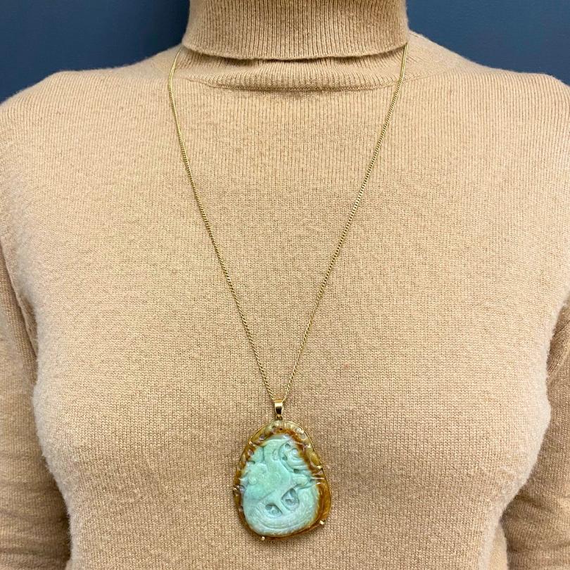 A vintage carved jade pendant and 18k gold chain necklace.
The pendant features a beautifully carved phoenix, a symbol of renewal and good fortune. The jade showcases a natural blend of soft green and warm honey tones. The phoenix appears in motion,