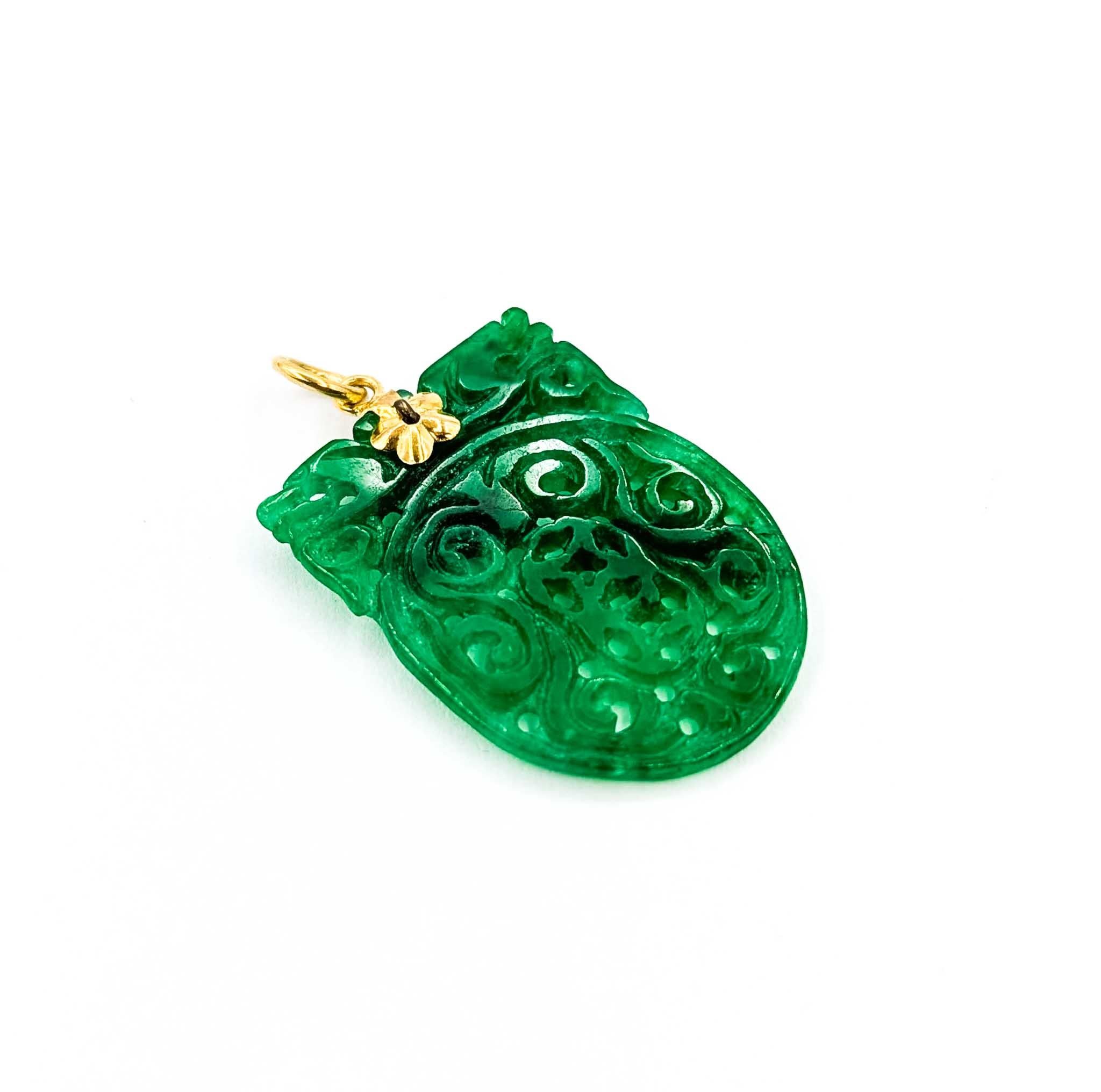 Ce pendentif remarquable est réalisé en or jaune 14k et présente une pièce centrale en jade magnifiquement sculptée mesurant 34 x 11 mm. Le jade, qui pèse 2,74 grammes, est orné de motifs tourbillonnants et d'accents percés, mettant en valeur l'art