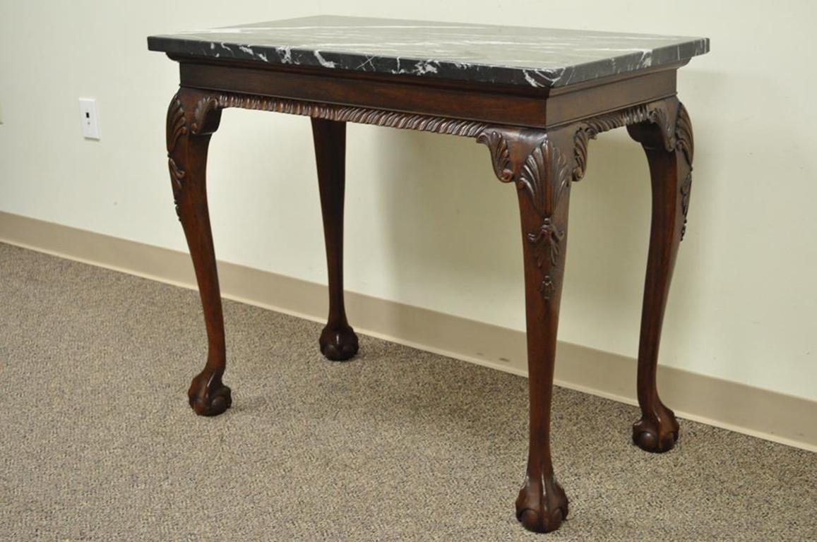 Quality carved solid mahogany Chippendale style marble top console or hall table. Item features shapely legs with shell carved knees terminating at ball and claw feet, Rope carved front skirt, finished back with non-rope carved rear skirt,