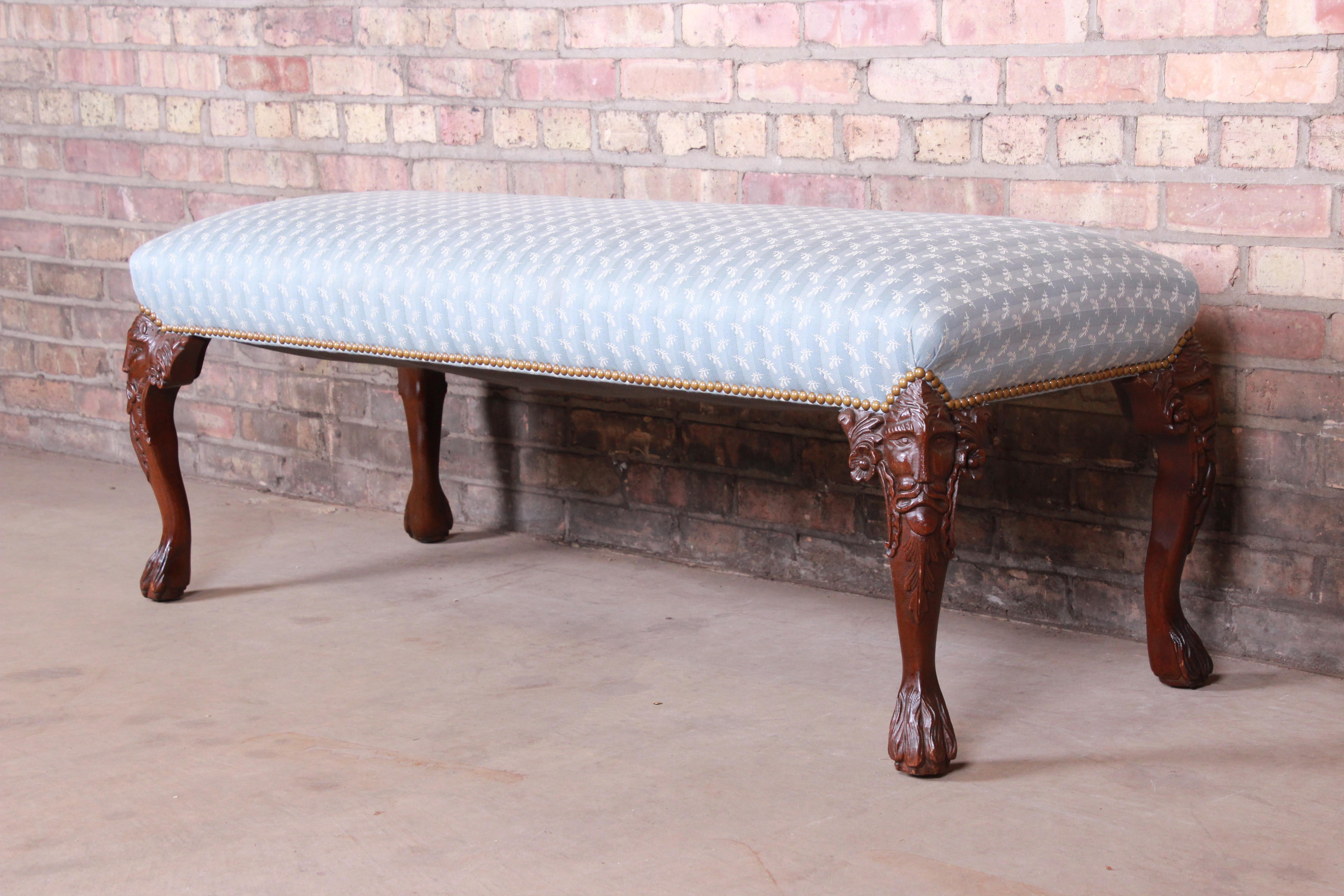 A gorgeous vintage carved mahogany upholstered window bench or bed bench,

20th century.

Mahogany cabriole legs with carved faces, and studded light blue and ivory upholstery.

Measures: 51.88