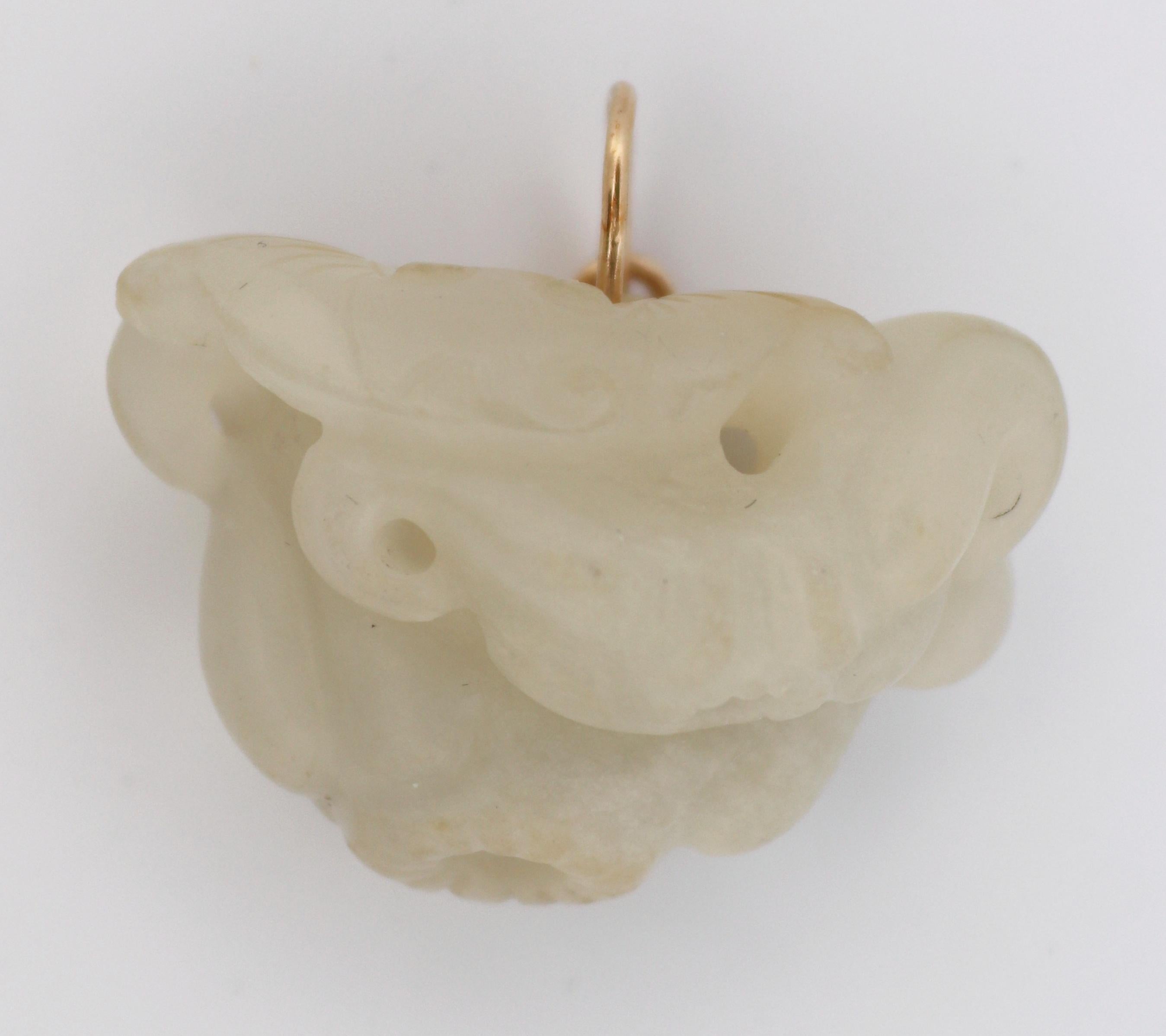 The carved white semi translucent nephrite “Mutton Fat” jade, depicts a bat drinking the nectar from a flower on top of two lotus flowers, completed by a 14k yellow gold wire bail, 30.0 X 16.3 X 20.0 mm, Gross weight 11.33 grams.