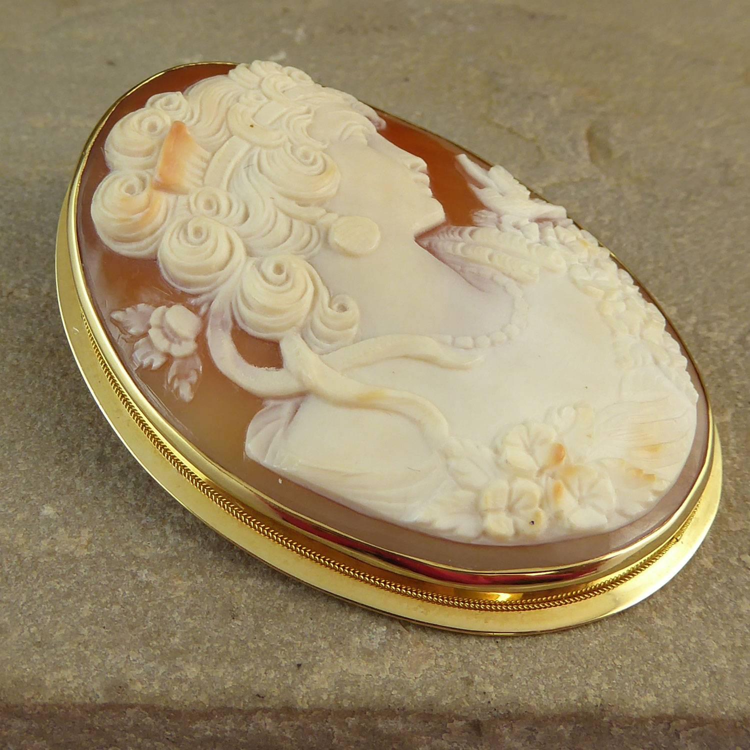 A beautifully carved vintage cameo of impressive size.  Expertly carved conch shell depicting a finely dressed and coiffured woman.  Her hairstyle is extremely ornate with curls around the face and tendrils escaping down the neck.  The  hairstyle is