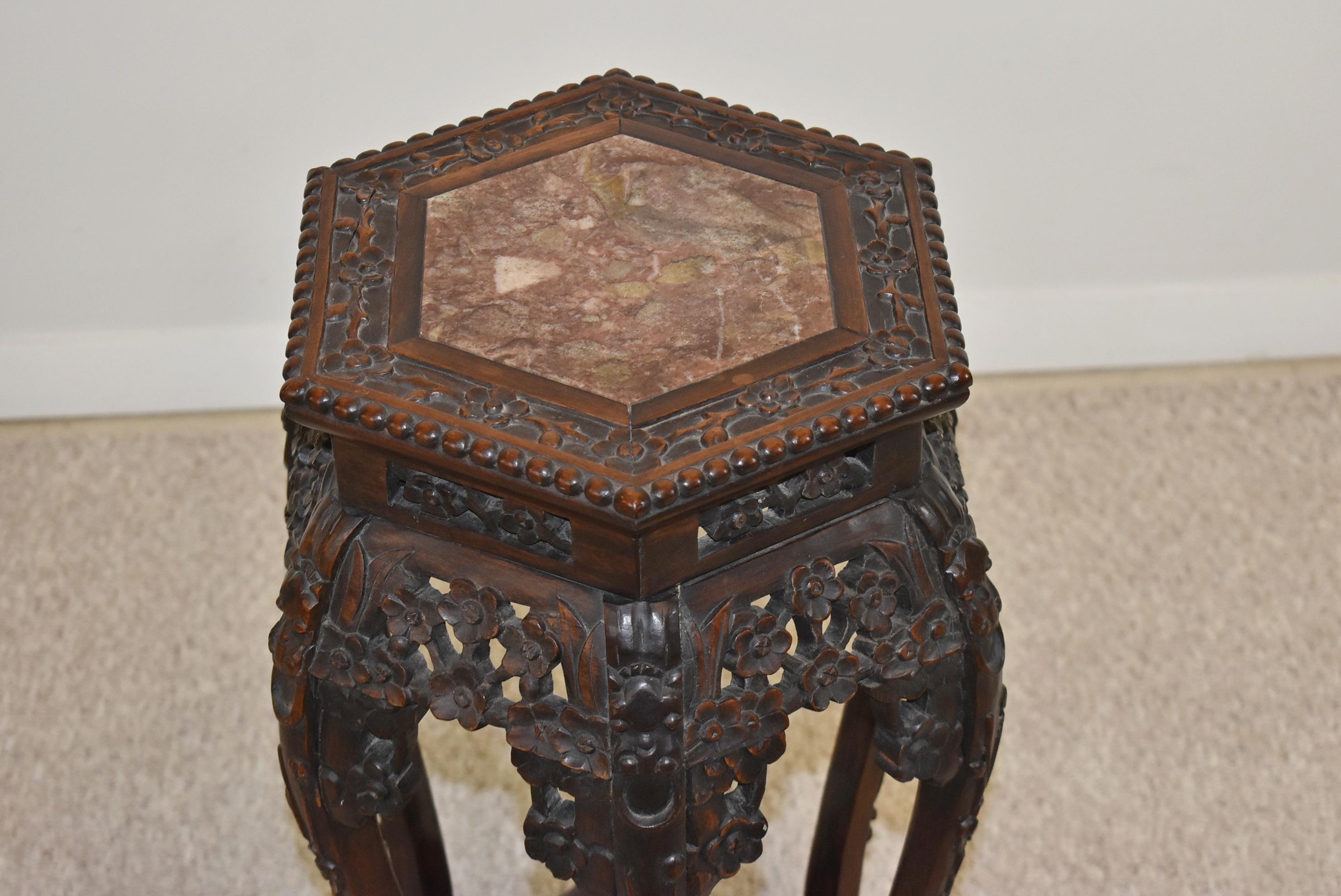 Vintage carved teak Asian stand. Circa 1920s. Intricately carved Chinese stand of flowers and lion heads with an inlaid hexagon soapstone top. Measures 13