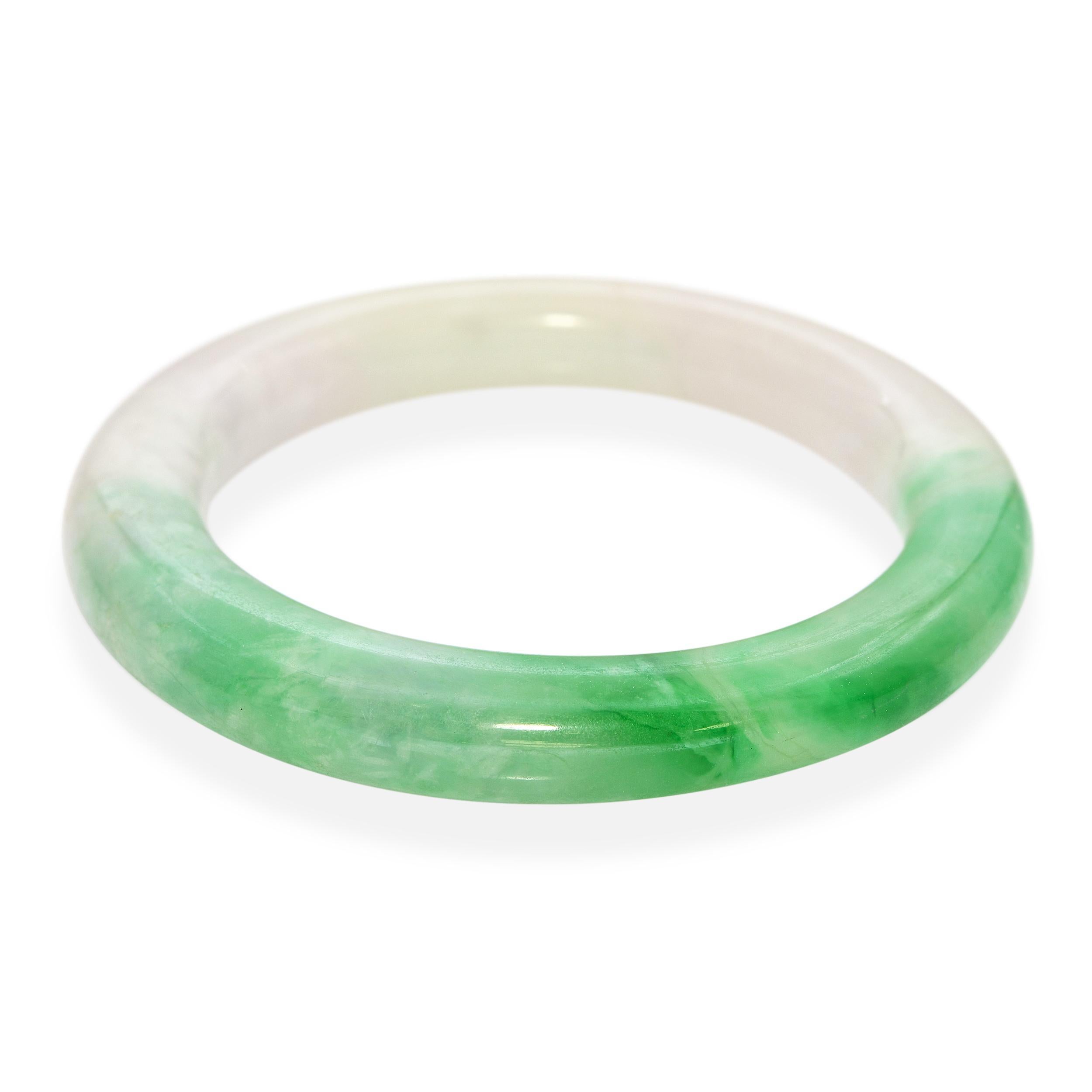 Ce bracelet vintage en jadéite sculptée est un bel exemple d'artisanat traditionnel et d'art naturel. La pièce est sculptée dans de la jadéite panachée, affichant un mélange de tons verts et blancs qui s'écoulent harmonieusement à travers la pierre.
