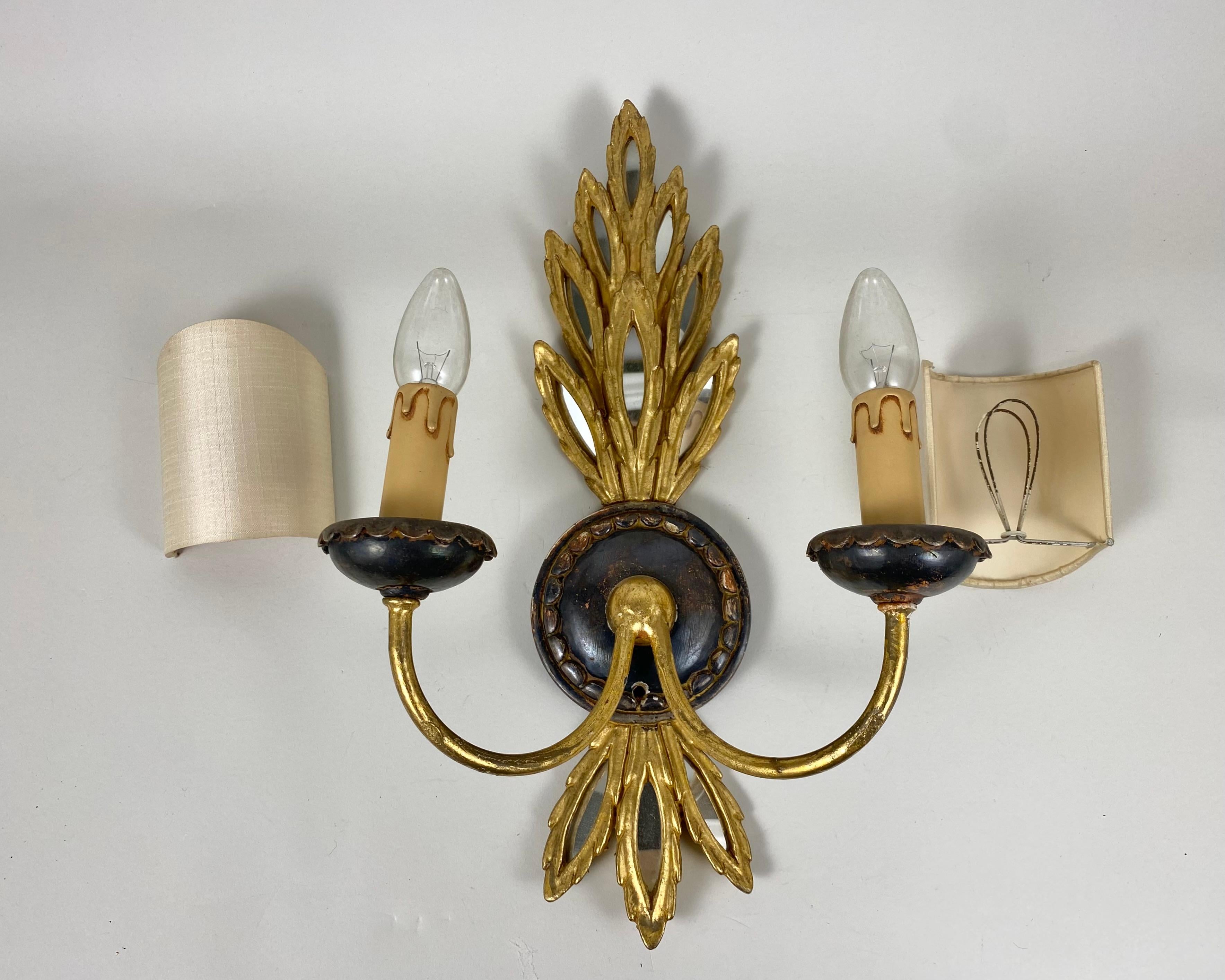 Vintage single sconce in the Empire style from Italy, circa 1950s.

Made of wood and gilded metal with decorative trim and mirror inserts. Decorated in a floral style. A cylindrical textile lampshade is located on two curved brackets of the