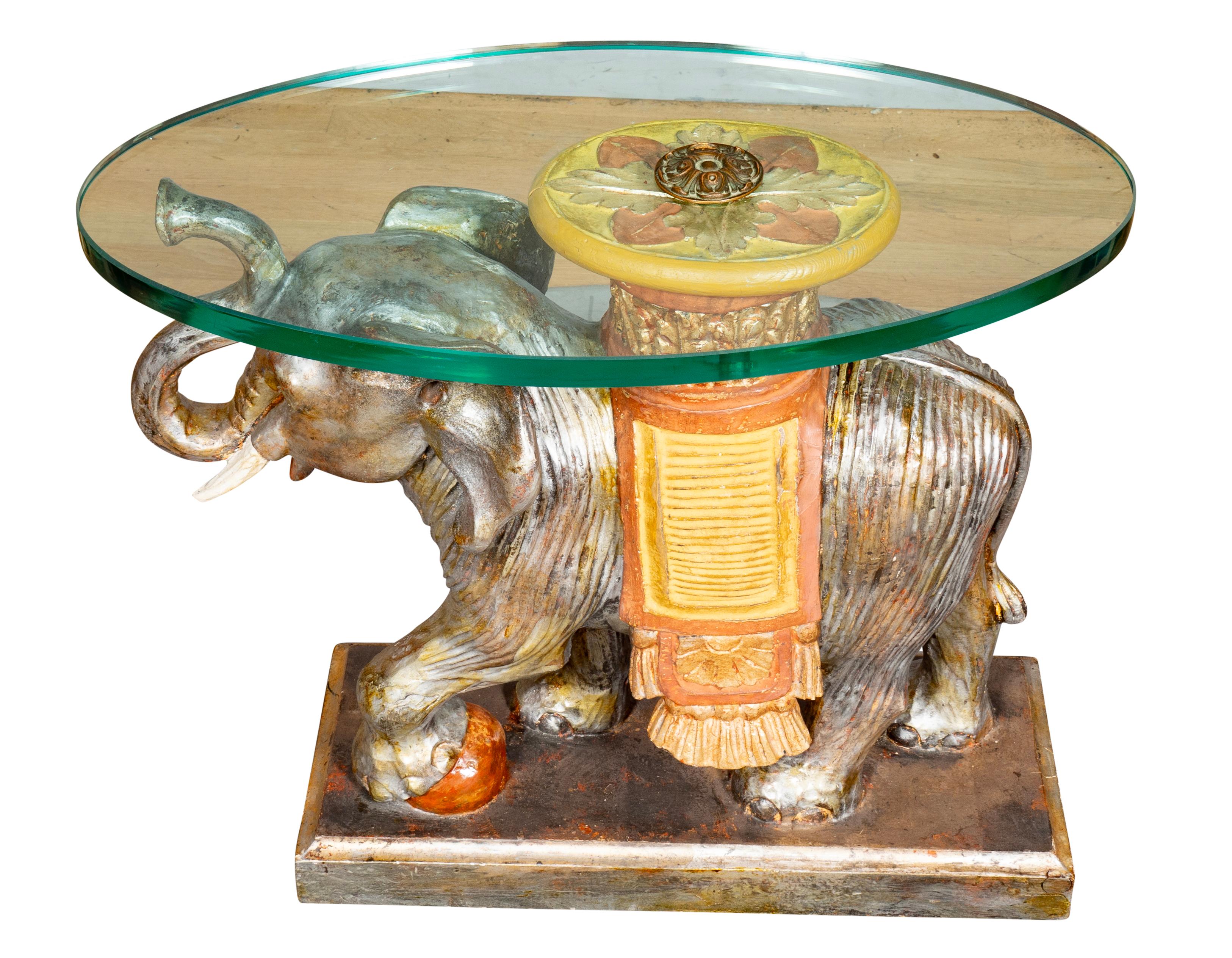With thick oval glass top with threaded rosette to hold it in place. The base a carved and painted elephant with one foot on a rock. Raised trunk and very decorative.