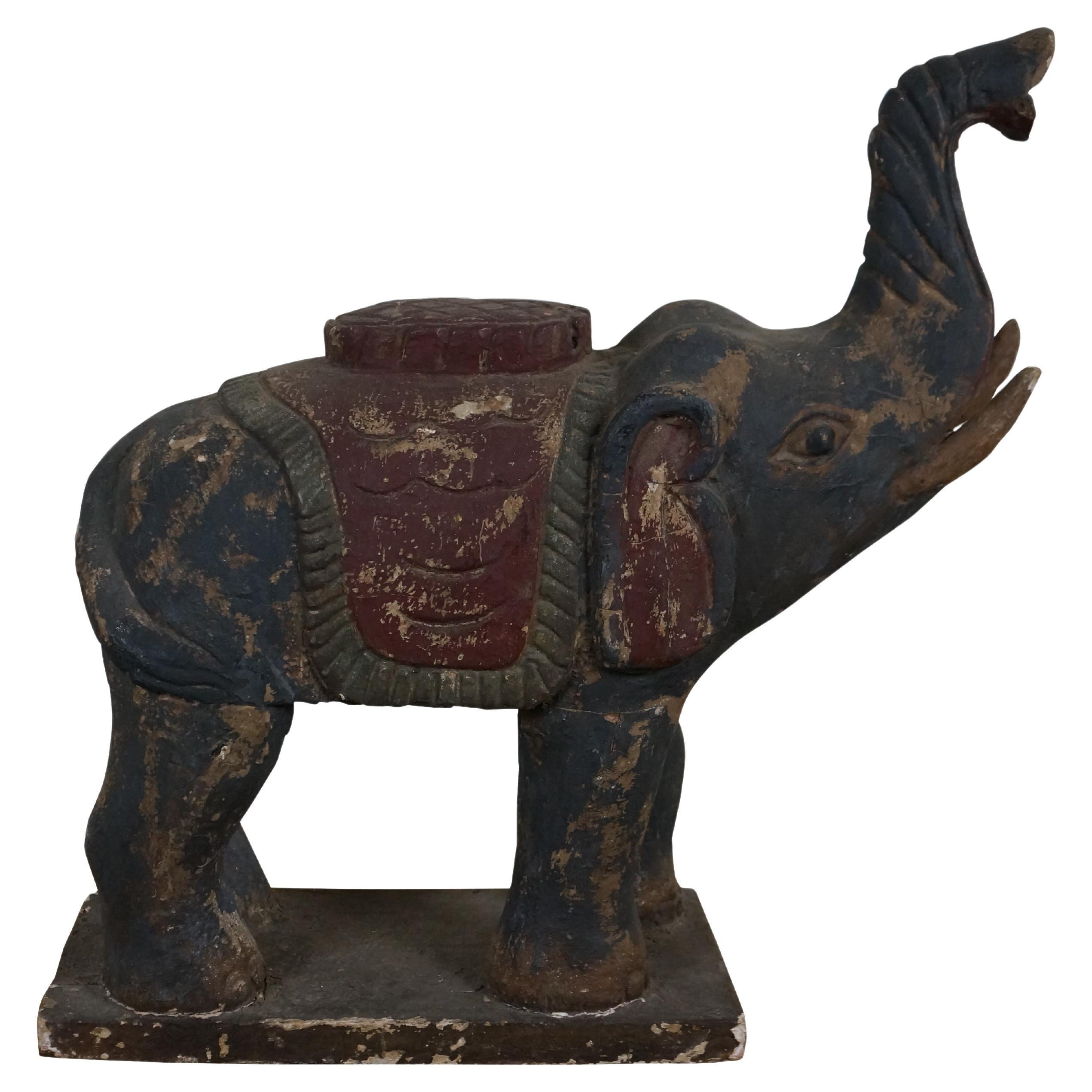 Scultura / statuetta di elefante d'epoca in legno intagliato a mano con fortunata proboscide sollevata, dipinta di nero con una sella rossa e verde, in piedi su una base rettangolare.

Dimensioni:
20