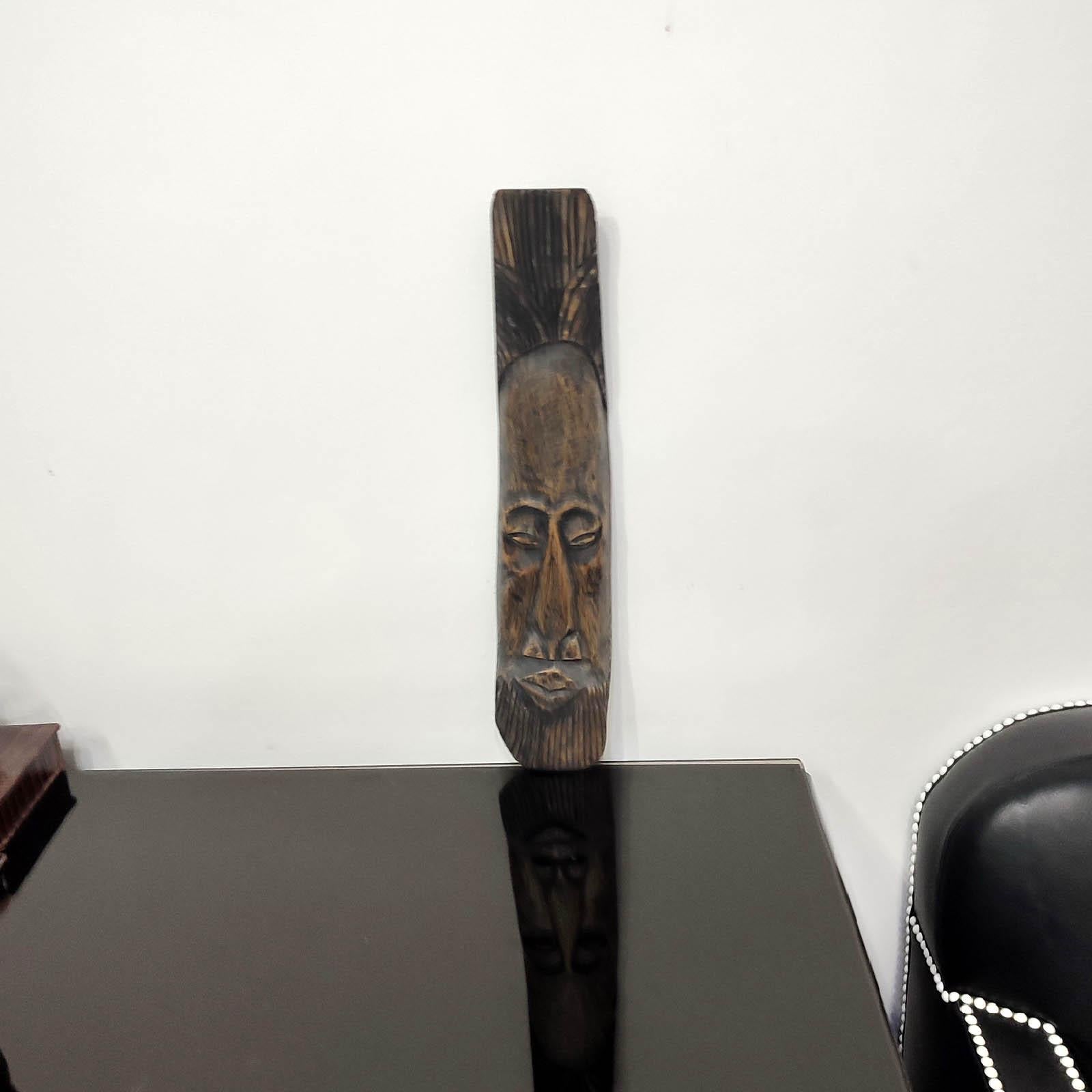 A hand carved wood wall mask, vintage from the 20th Century. African Folk Art. 
Handmade and carved from a single piece of exotic wood, in a manner specific to traditional African art. Signed with monogram on the underside. In a very good original