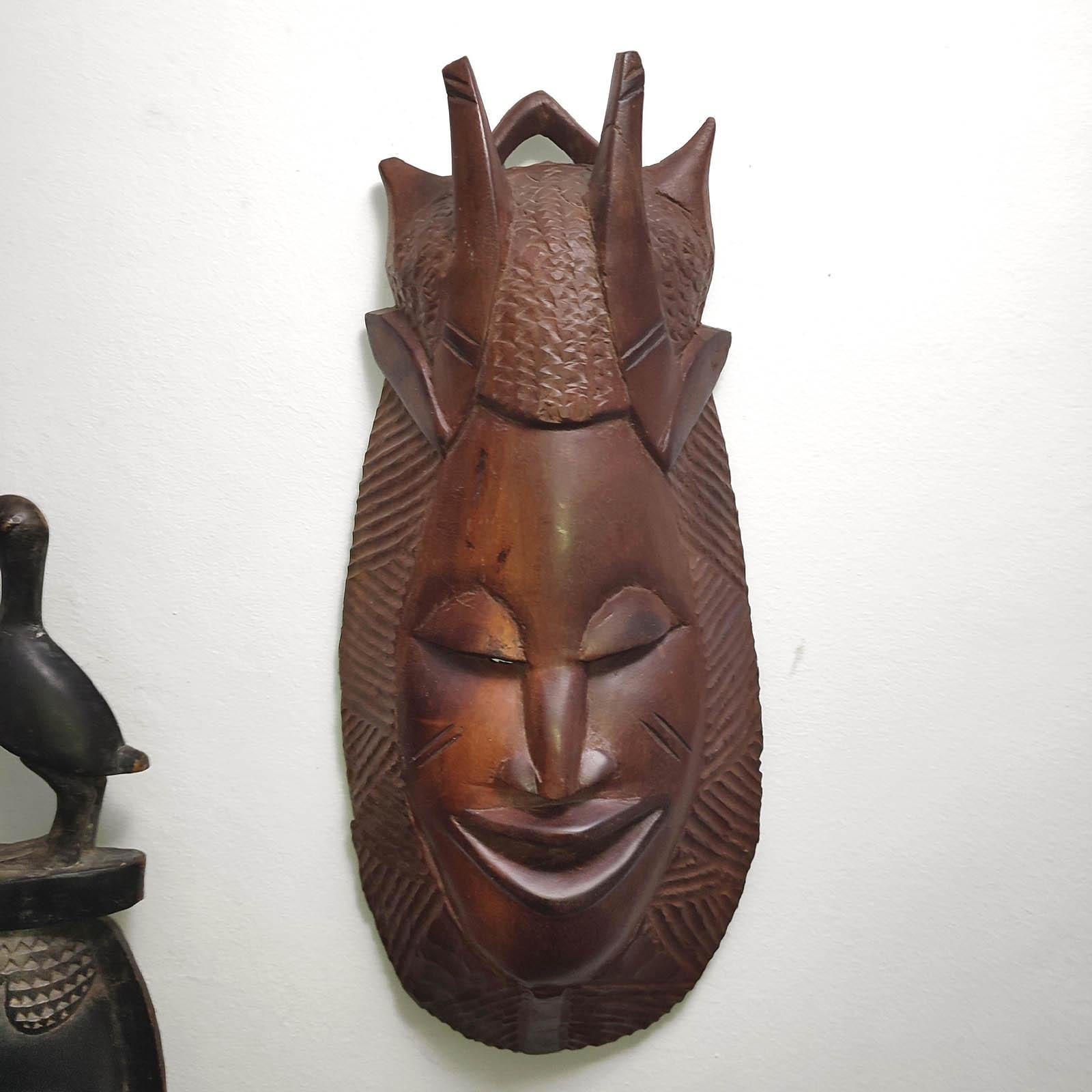 African mask handmade and carved from a single piece of exotic wood, in a manner specific to the traditional African art. Hand carved wall mask with decorative geometric ornaments, designed to reflect the initiation ritual of “scarification”. In a