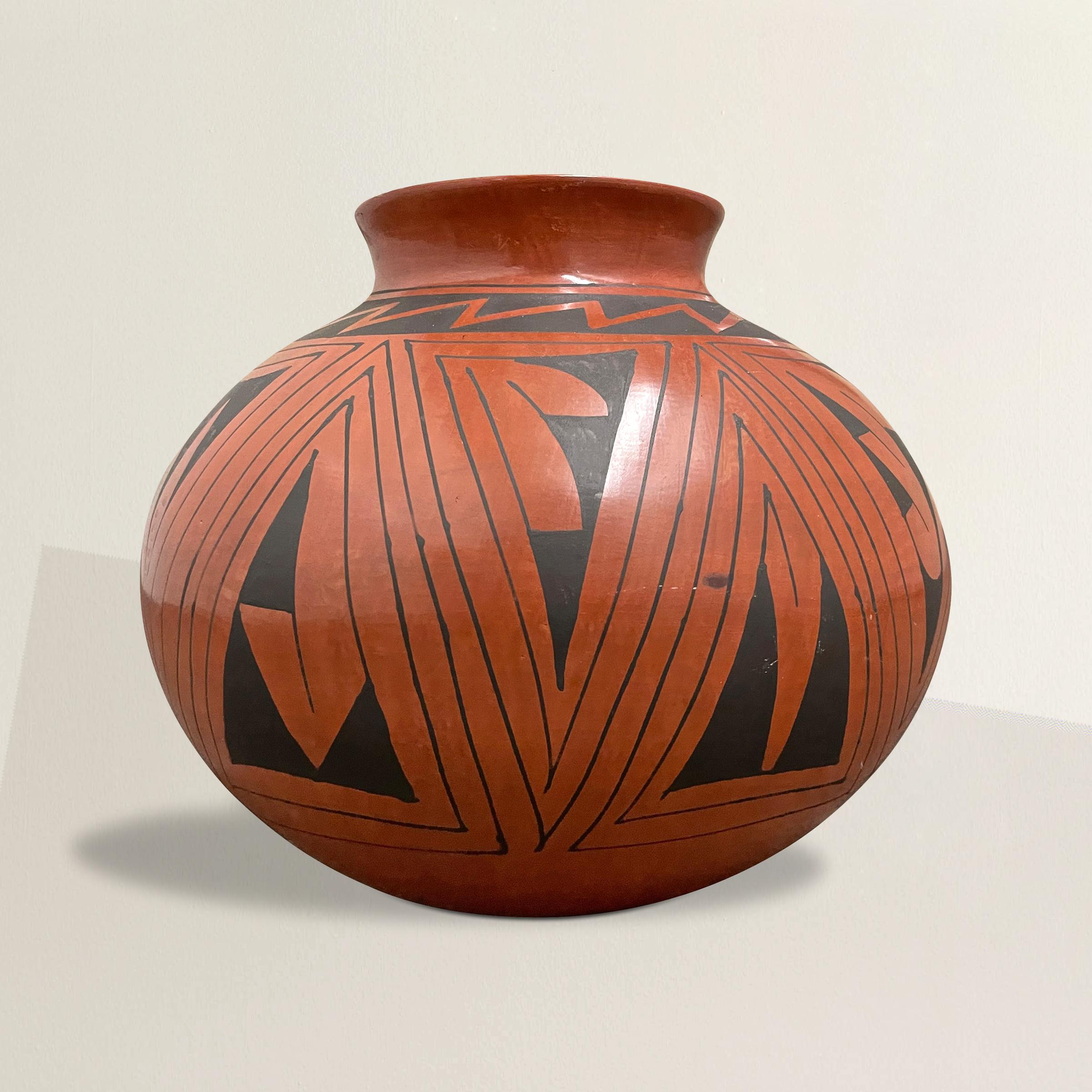 A striking vintage Casa Grandes pottery vase with a large belly, narrow neck, and wide lip, and decorated with black geometric patterns repeated around the pot. Signed on the bottom.
