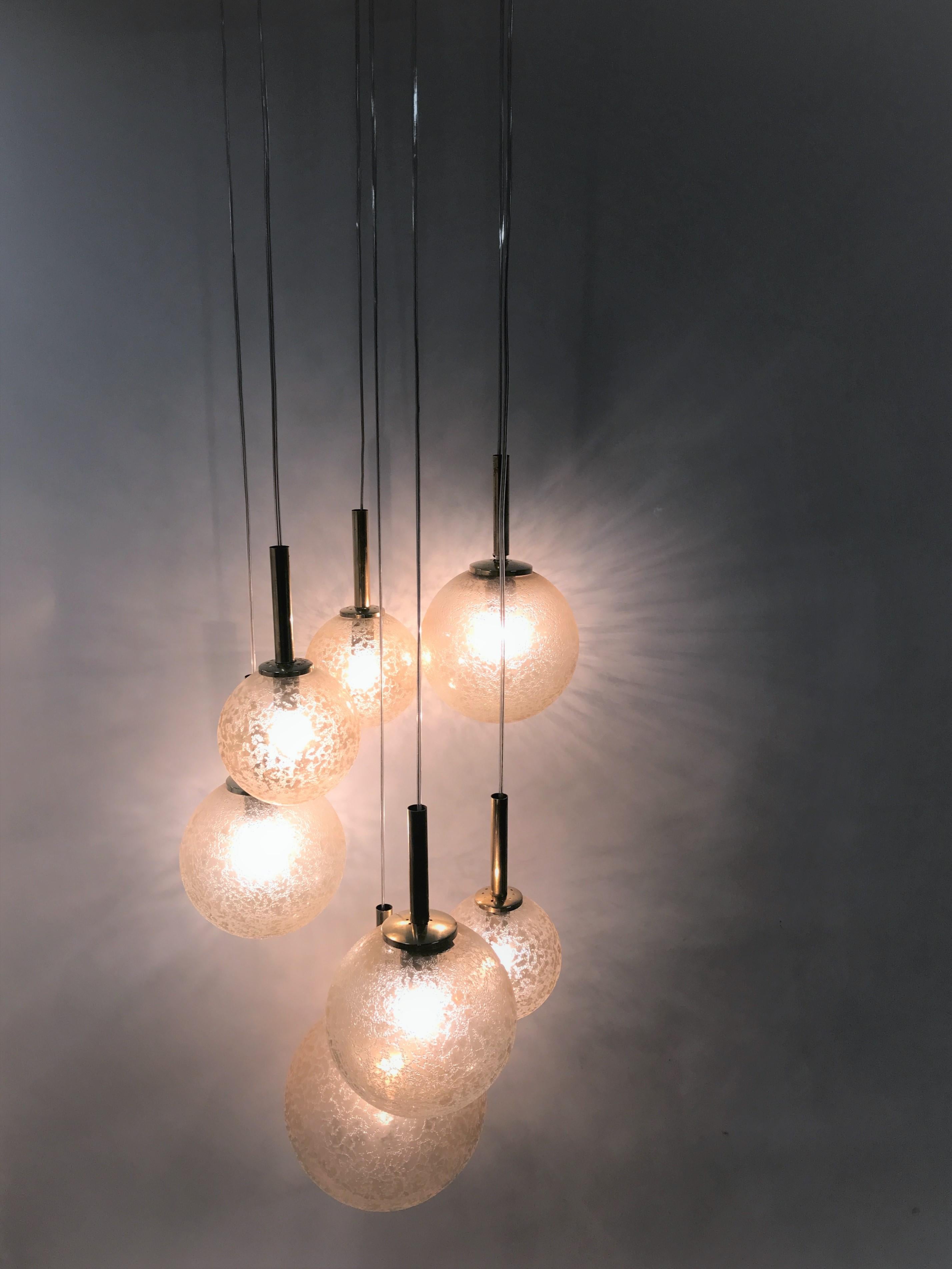 Midcentury brass and glass chandelier bu Doria Leuchten.

This multi level or cascading chandelier consists of 7 glass/gold globes of different sizes.

The chandelier's height can be adjusted with the cables.

Completely rewired and tested.
