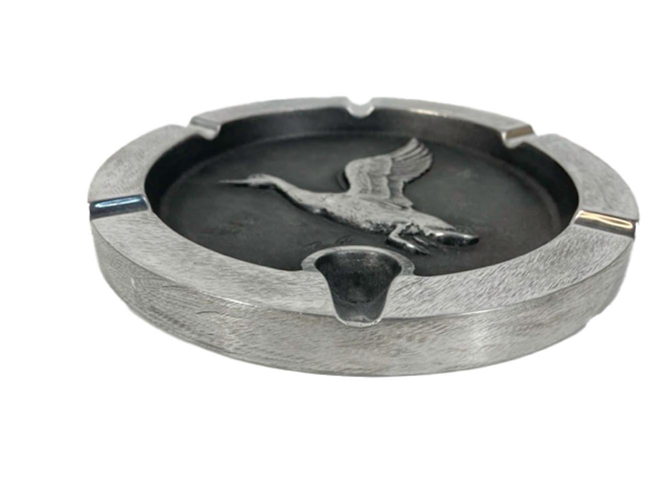 Vintage, large scale, hand finished, cast aluminum cigar / pipe ashtray with a relief cast flying goose in the center on a blackened ground and having 5 cigar and 1 pipe rest molded in the raised rim.