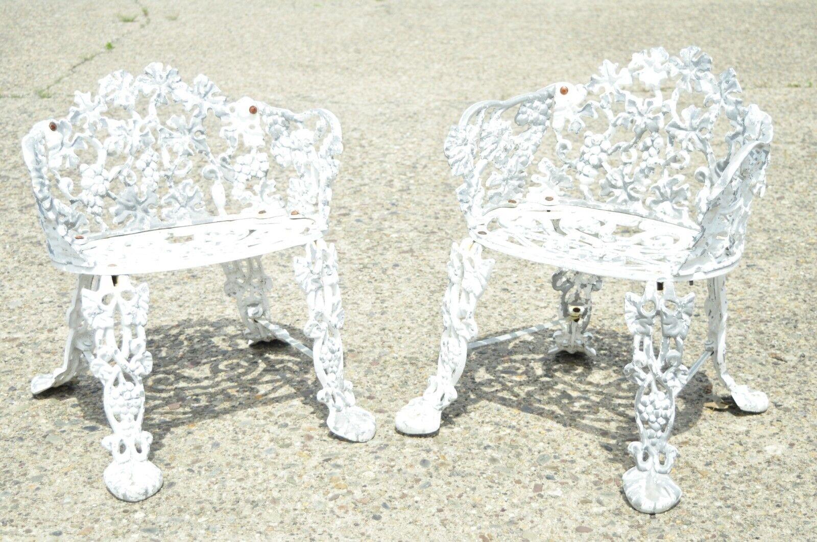 Vintage cast aluminum grape and vine leaf outdoor garden chair set with table. Item features (2) small armchairs, (1) small round side table, cast aluminum construction, grape and vine leaf pattern, white painted weathered finish, very nice vintage