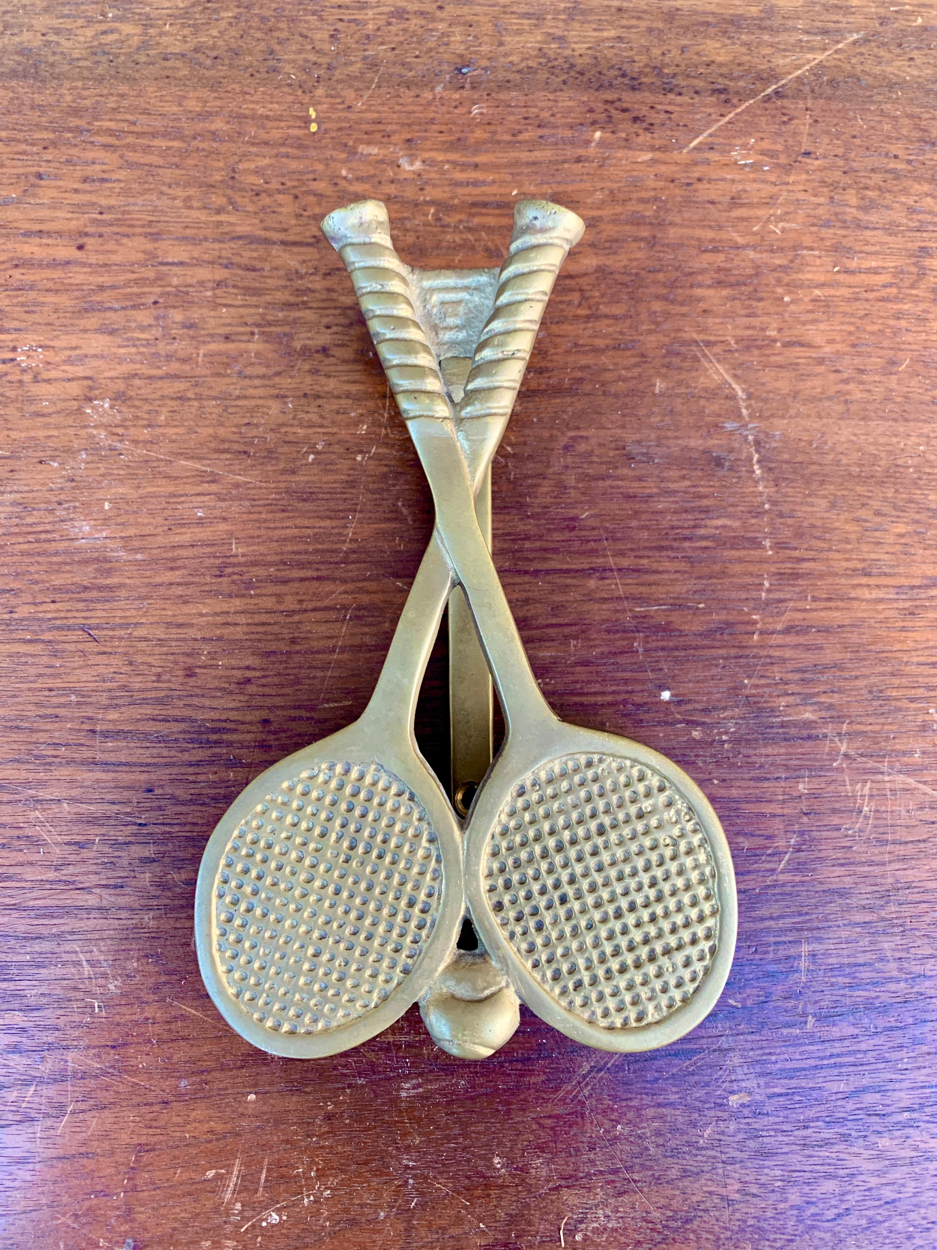 A beautiful cast brass door knocker in the form of two tennis rackets and a tennis ball.

USA, Mid-20th Century

Measures: 3.75