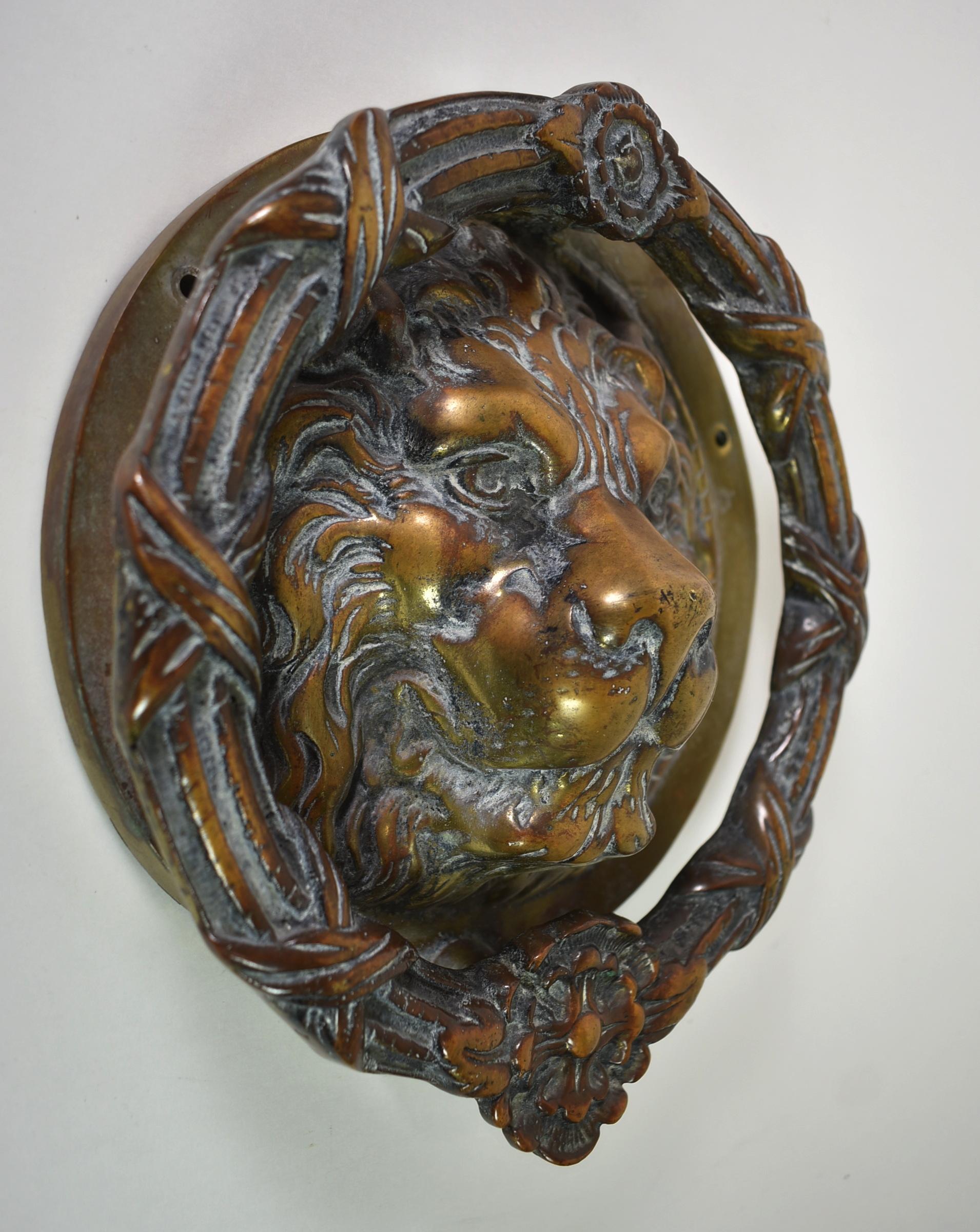 Vintage large scale cast brass lion head door knocker. Border has high relief floral wreath details. Back plate is 8.25