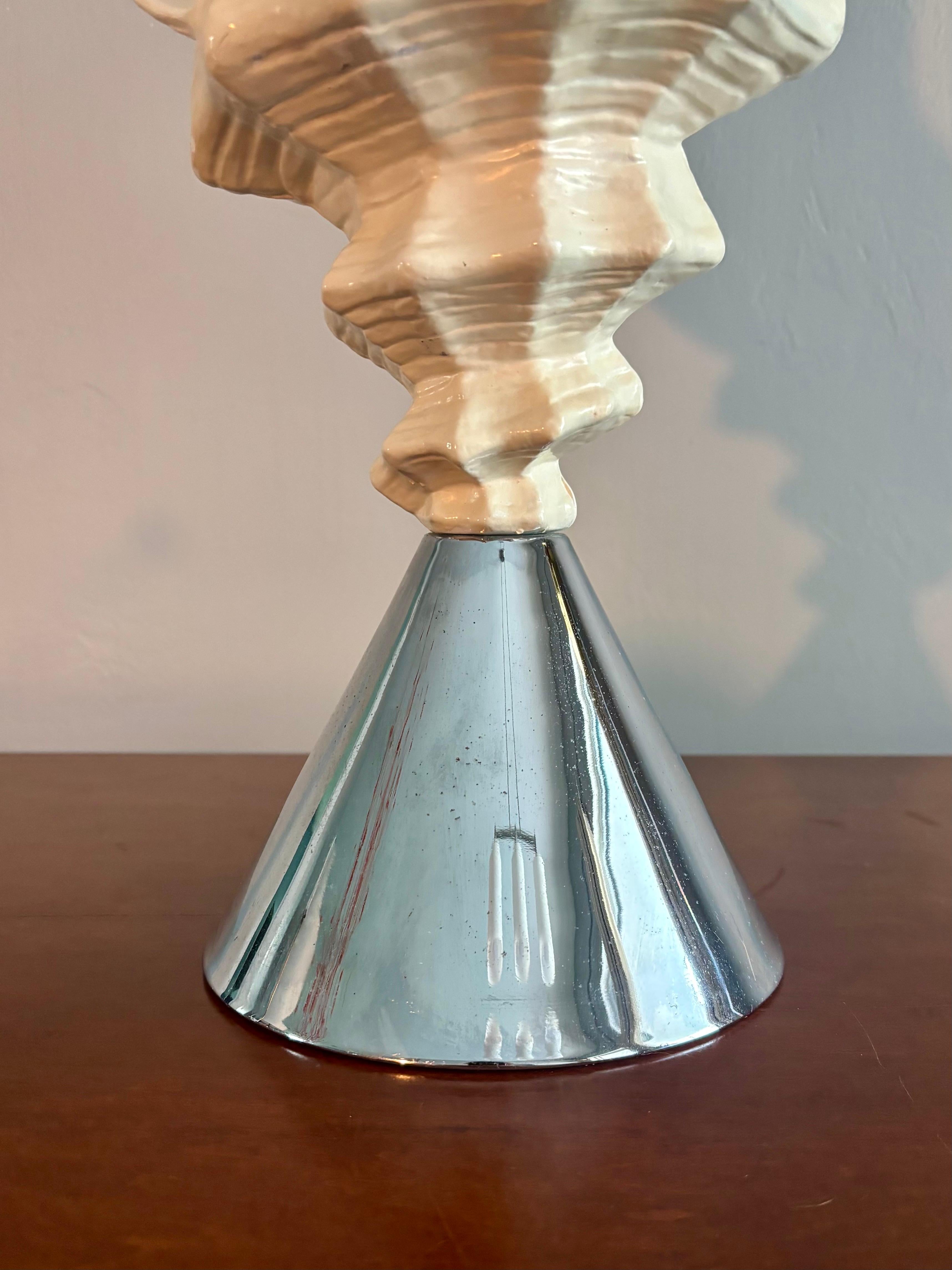 Muschelhornlampe im Vintage-Küstenstil. 

Eine schlichte, aber faszinierende Leuchte, die Elemente des Mid Century Modern mit Hollywood Regency verbindet. 

Gegossene Muschelschale mit weißer Beschichtung, die an einem umgekehrten Chromkegel