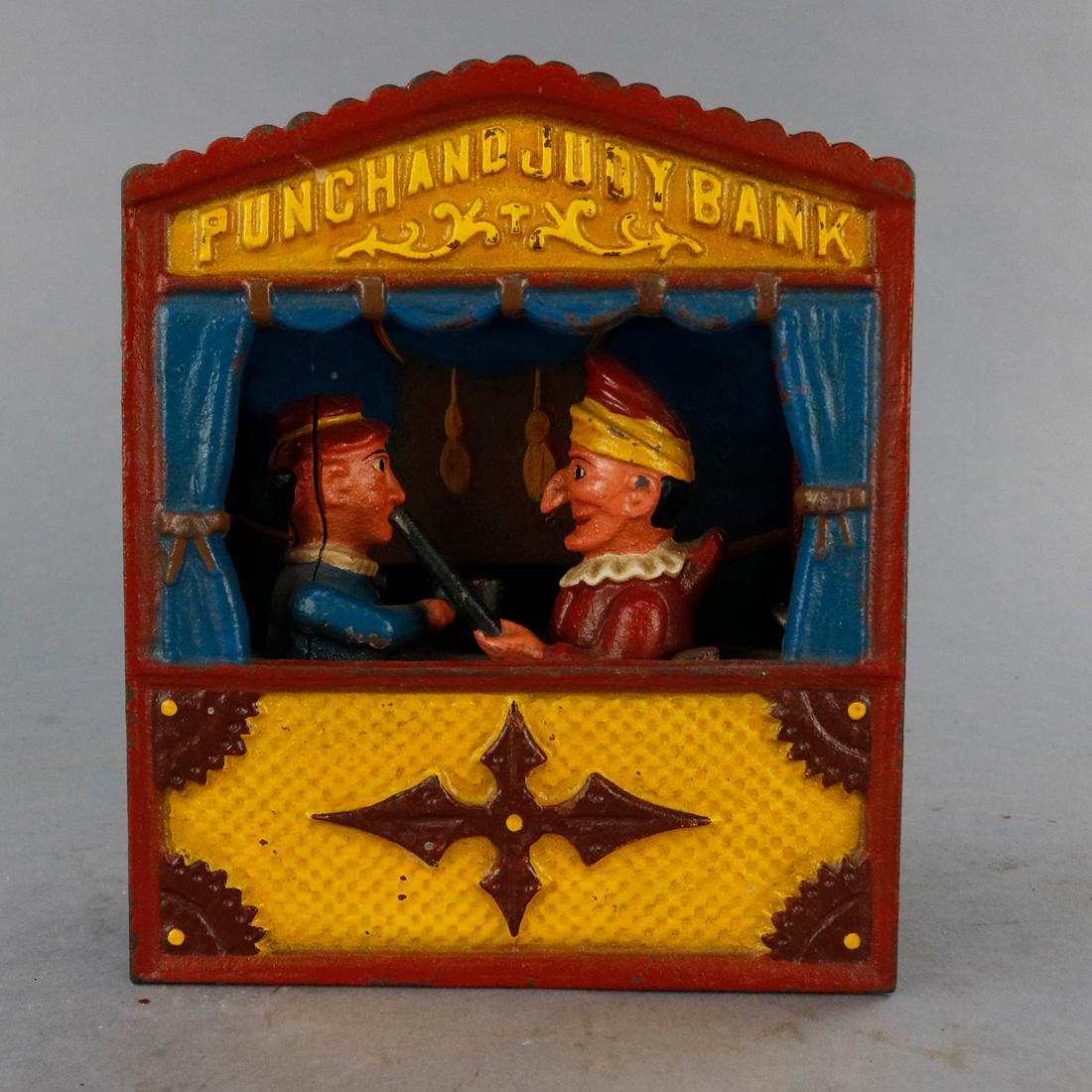 A vintage book of knowledge Punch & Judy mechanical bank offers polychrome cast construction with puppet stage and figures with embossed title, underside reads 