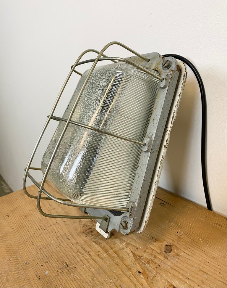 This cast iron wall lamp was made by Polam Wilkasy in Poland during the 1960s.. It features cast iron body, a ribbed clear glass and steel grid. New porcelain socket for E 27 lightbulbs and wire.The weight of the lamp is 5 kg.
  