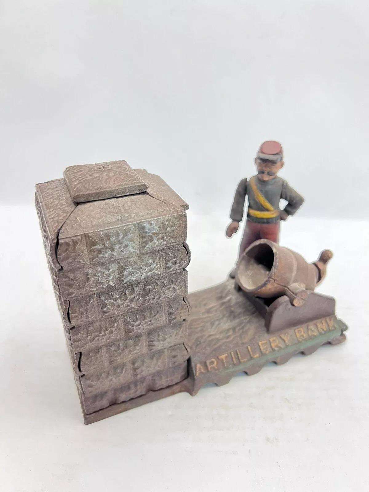 Vintage Cast Iron Still Bank Artillery Bank Coin Bank Book of Knowledge. Circa Late 20th Century. Measurements: 6.25