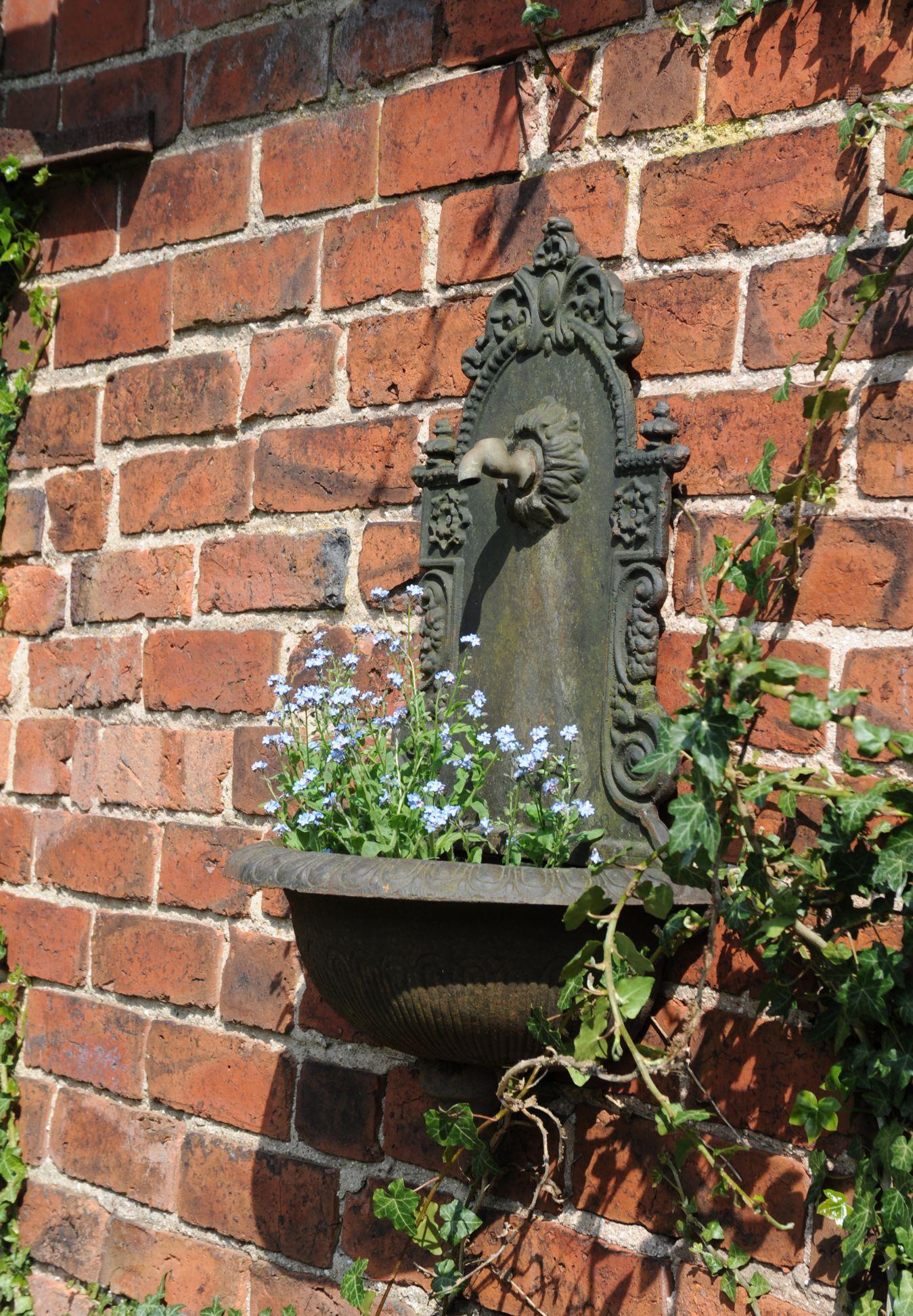 A lovely antique/vintage cast iron wall fountain, old paint with rust and remains of a brass tap, a beautiful planter or reinstate as a fountain.