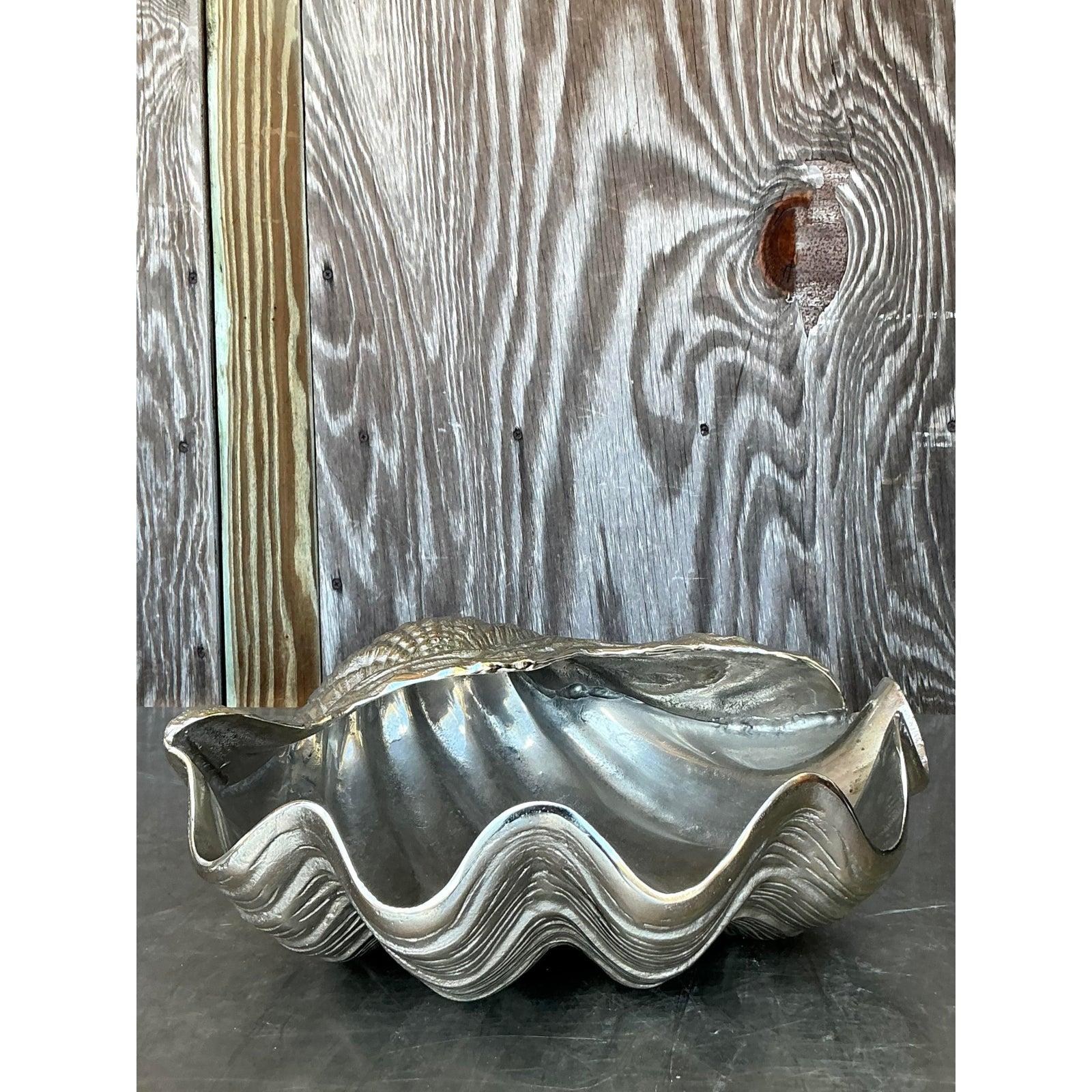 Porta l'eleganza costiera nel tuo spazio con questa splendida conchiglia gigante in metallo fuso vintage. Sapientemente realizzato con intricati dettagli realistici, questo sostanzioso pezzo decorativo cattura la bellezza organica del mare in una