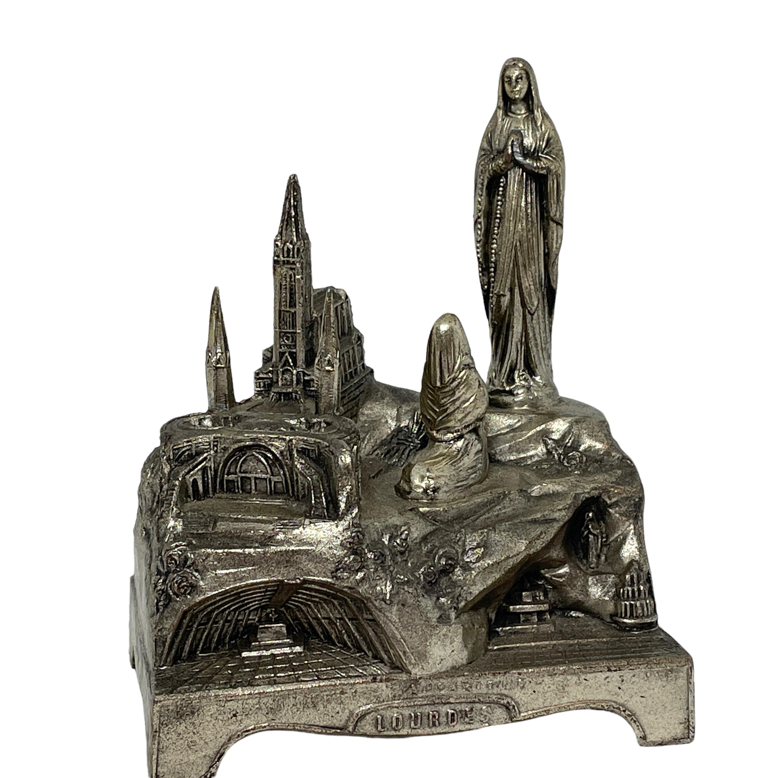 This vintage silvered Music Box was a souvenir from a pilgrims journey to the famous City of Lourdes in France. It is made of metal and wood. The music box plays a nice melody and is in working condition. A nice addition to any collection.
 