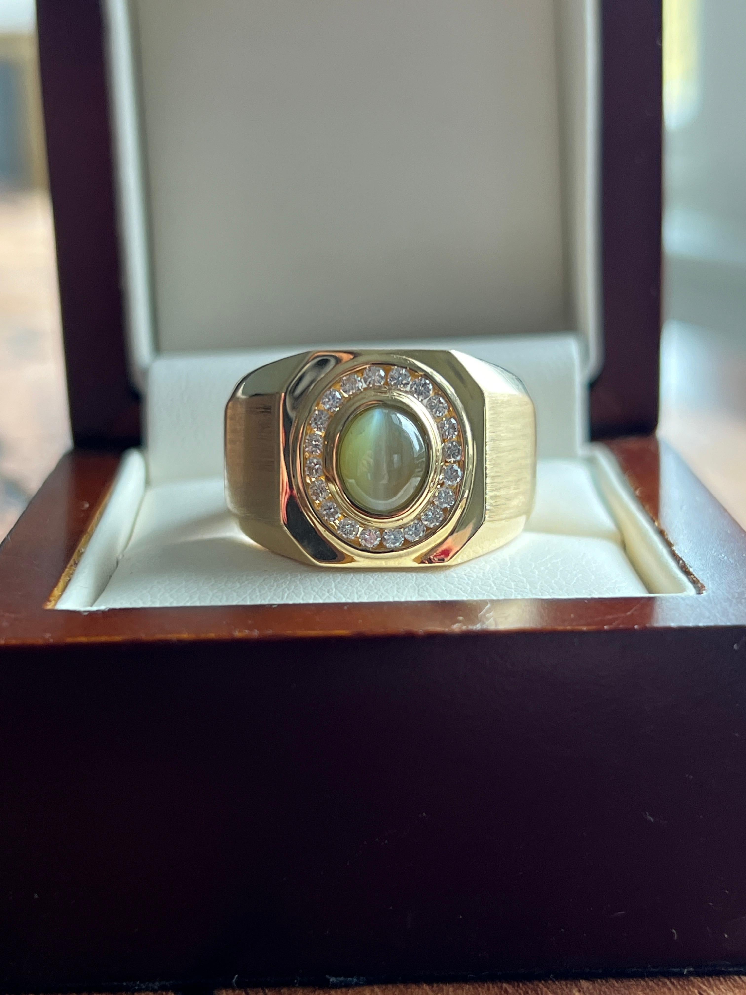 Questo straordinario anello di proprietà, realizzato in oro giallo 18 carati, presenta al centro un crisoberillo cabochon a forma di occhio di gatto, celebre per la sua naturale chatoyancy, una banda di luce riflettente che si muove sulla pietra